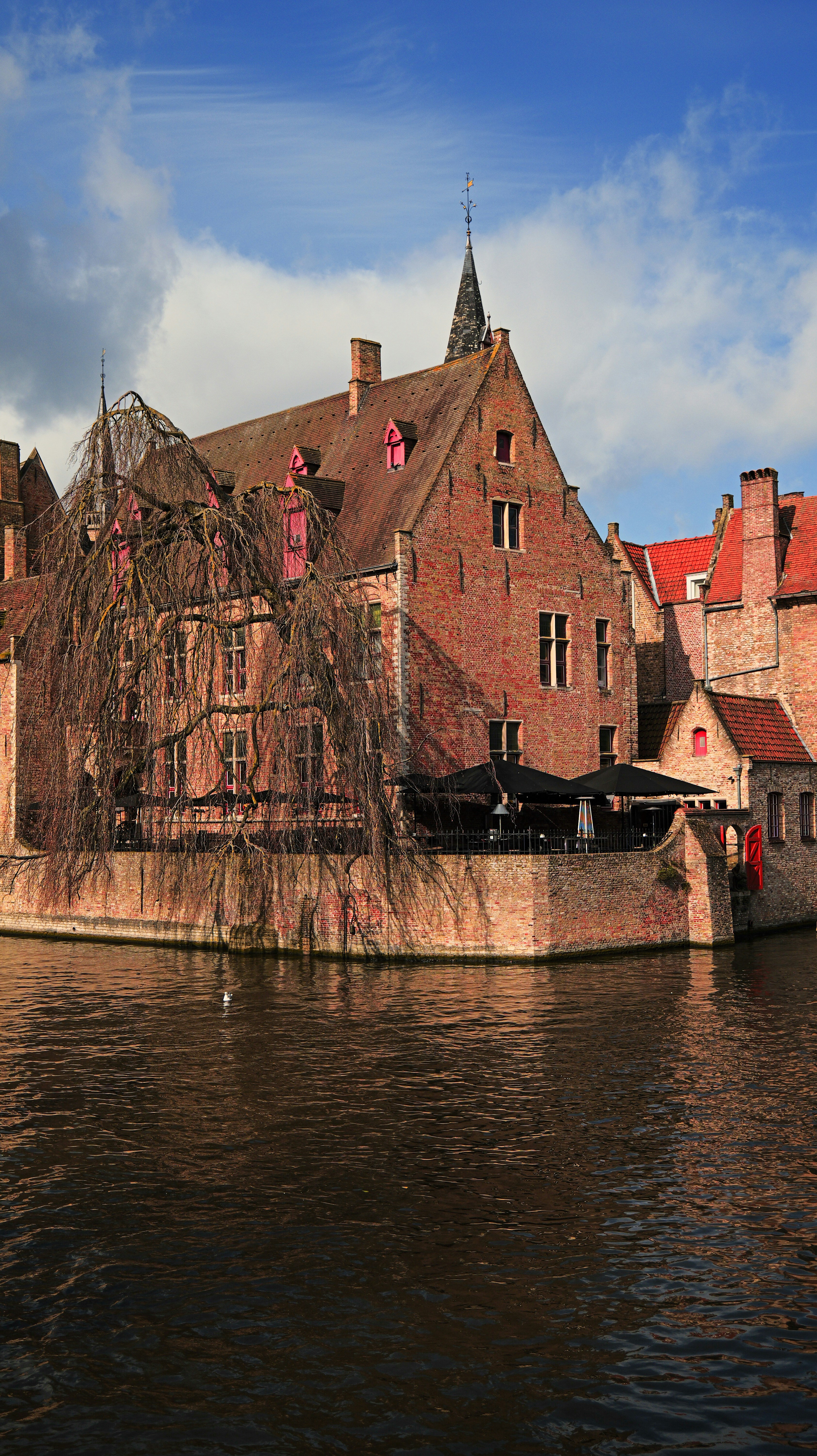 Historic brick buildings line a canal under a cloudy sky. - historic-brick-buildings-line-a-canal-under-a-cloudy-sky-yR2XPtldmgQ