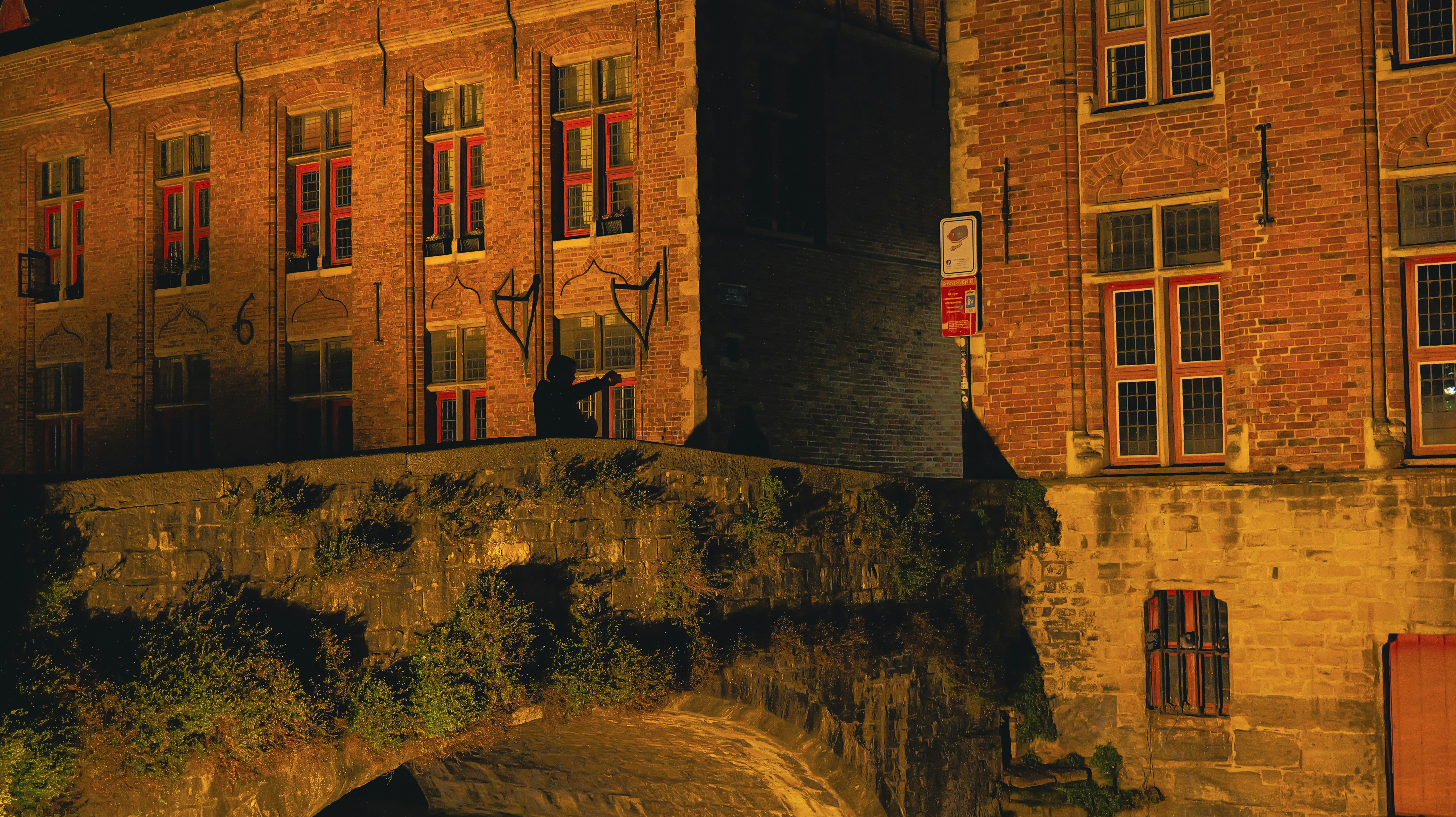 Old brick buildings illuminated at night with dark alley. - old-brick-buildings-illuminated-at-night-with-dark-alley-WLCgn-eJWLc