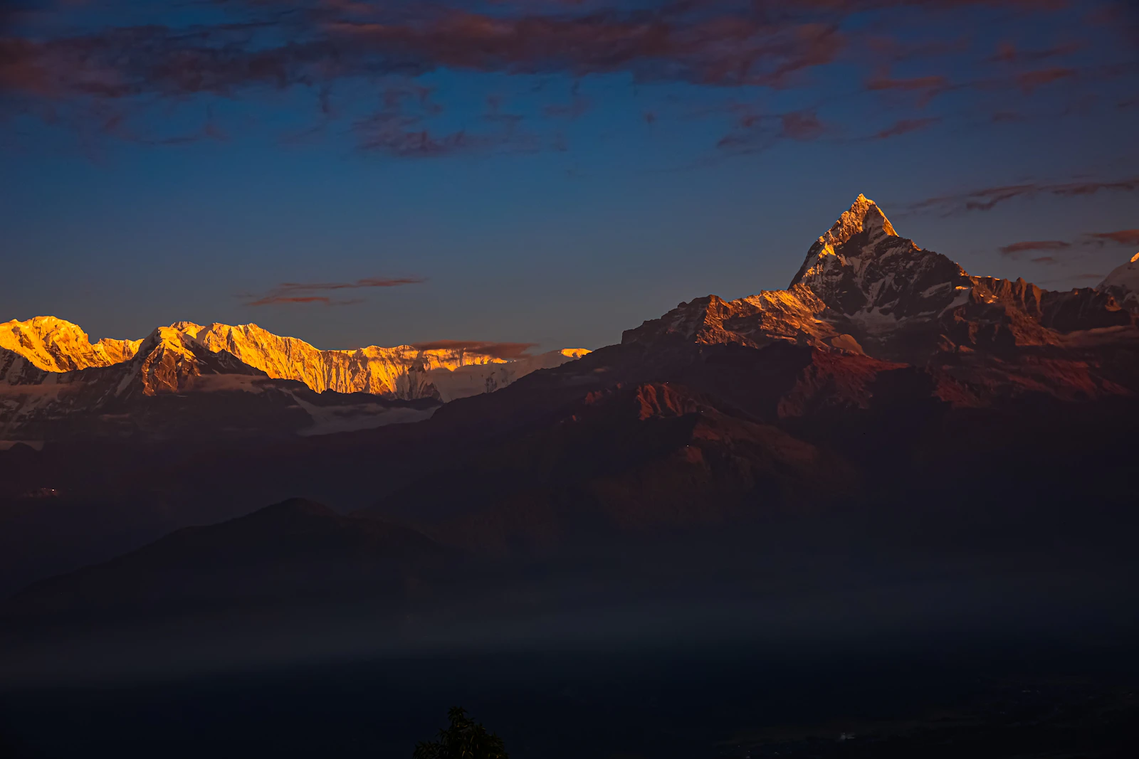 Machhapuchhre and the Annapurna range catching first gold light above dark foothills, Nepal