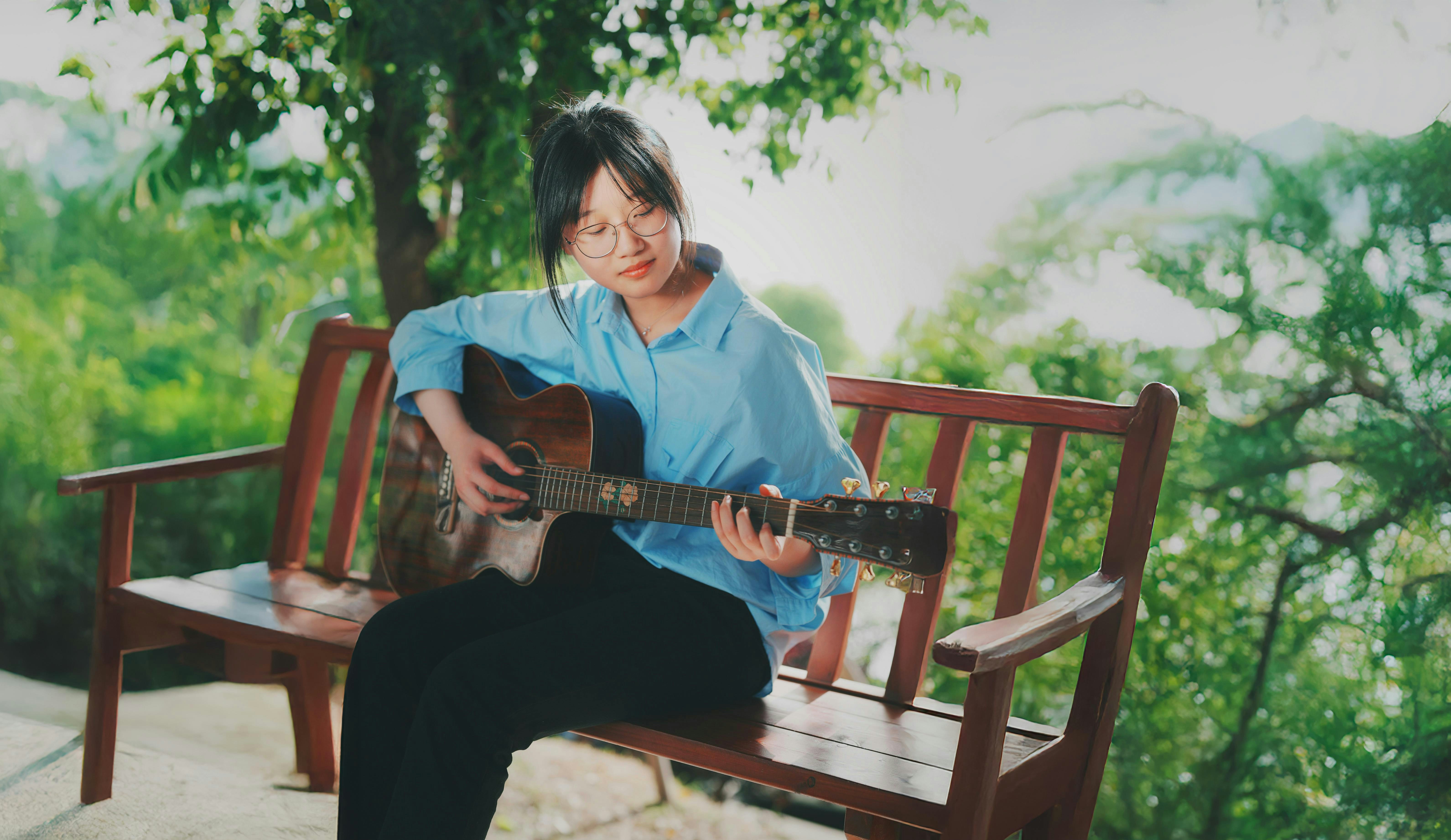 Young woman playing guitar on a wooden bench outdoors. photo – Free ...
