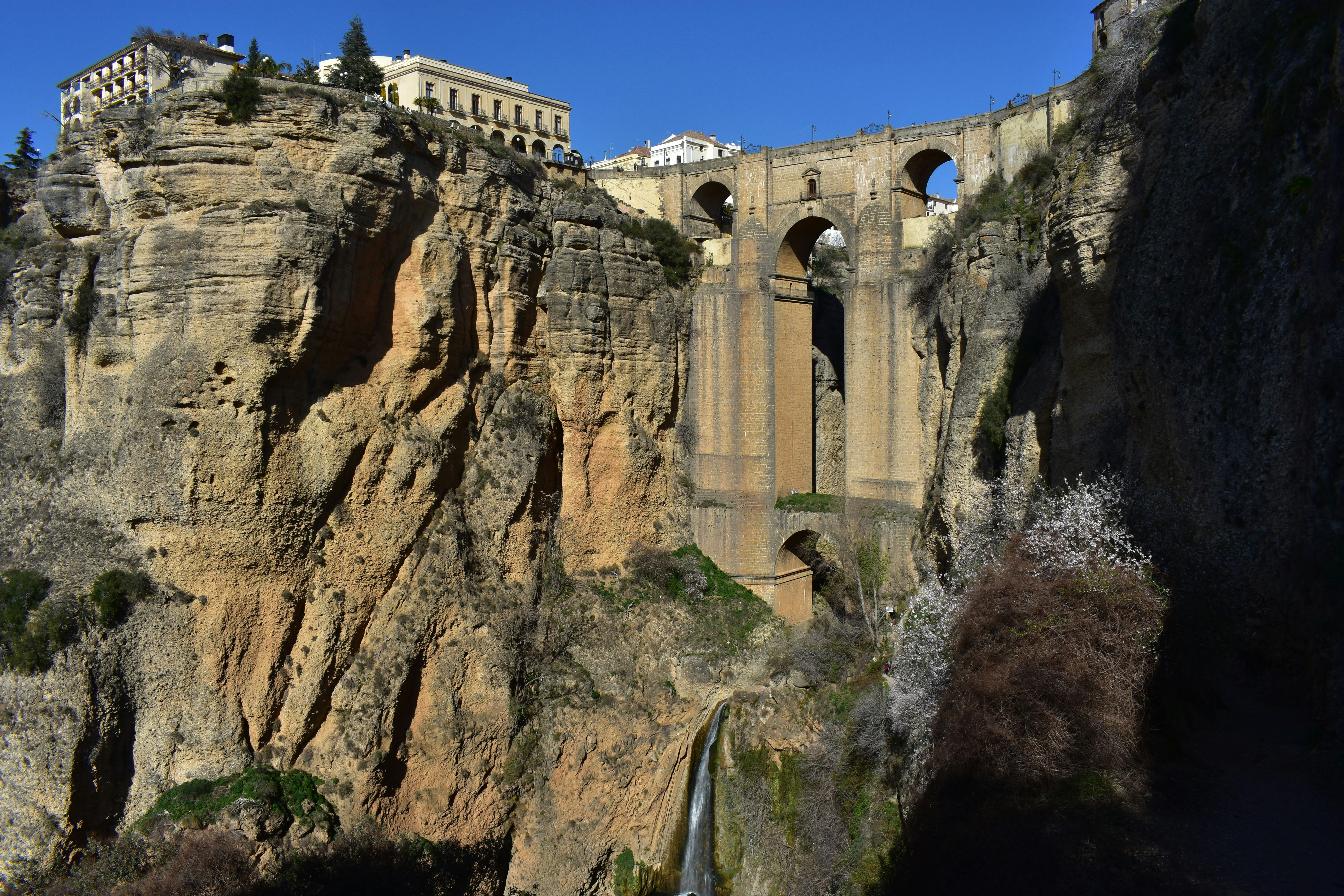 Historic bridge spans a deep gorge with waterfall.