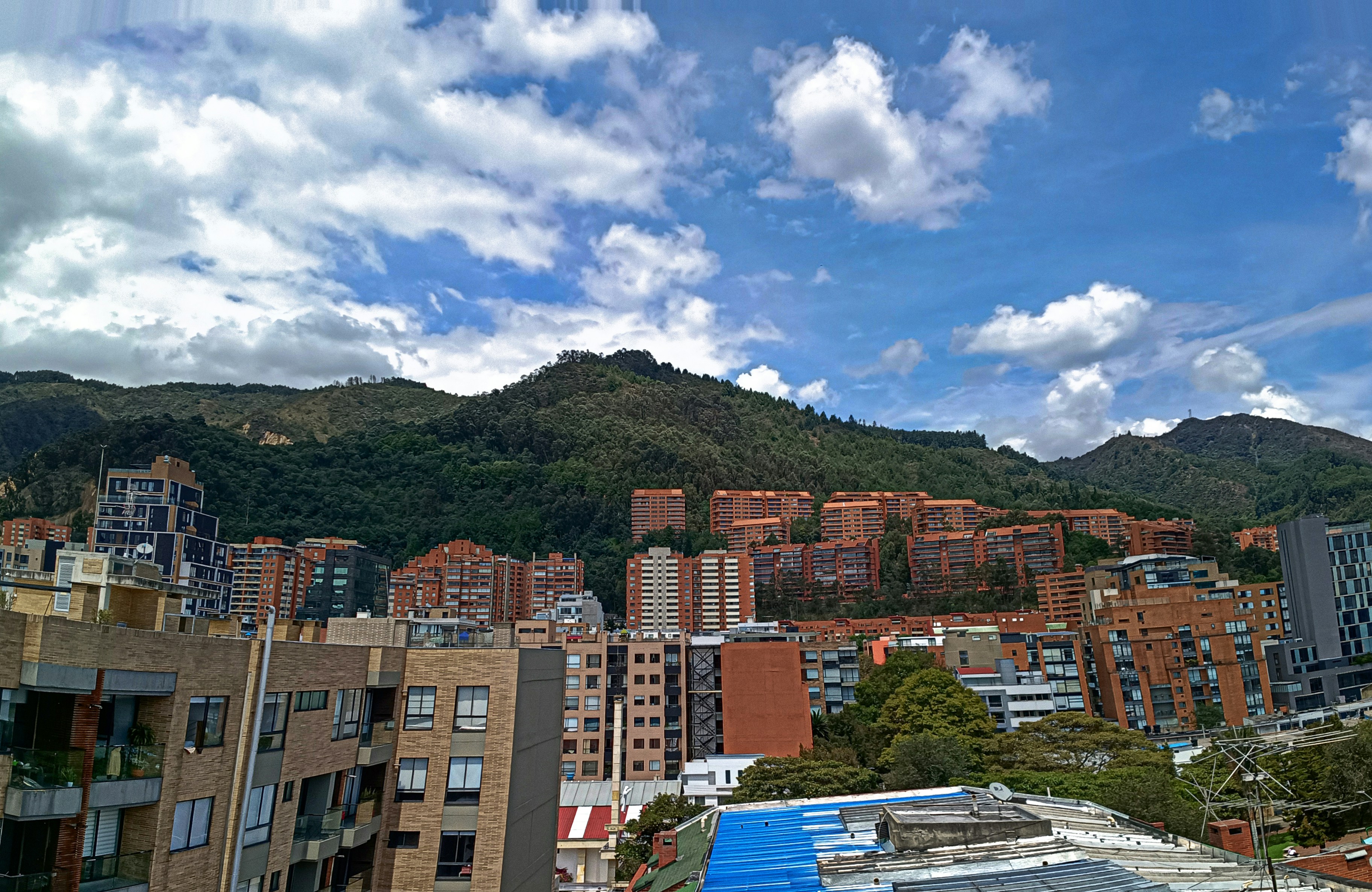 Edificios de la ciudad enclavados al pie de una montaña verde.
