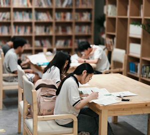Students studying at tables in a library.