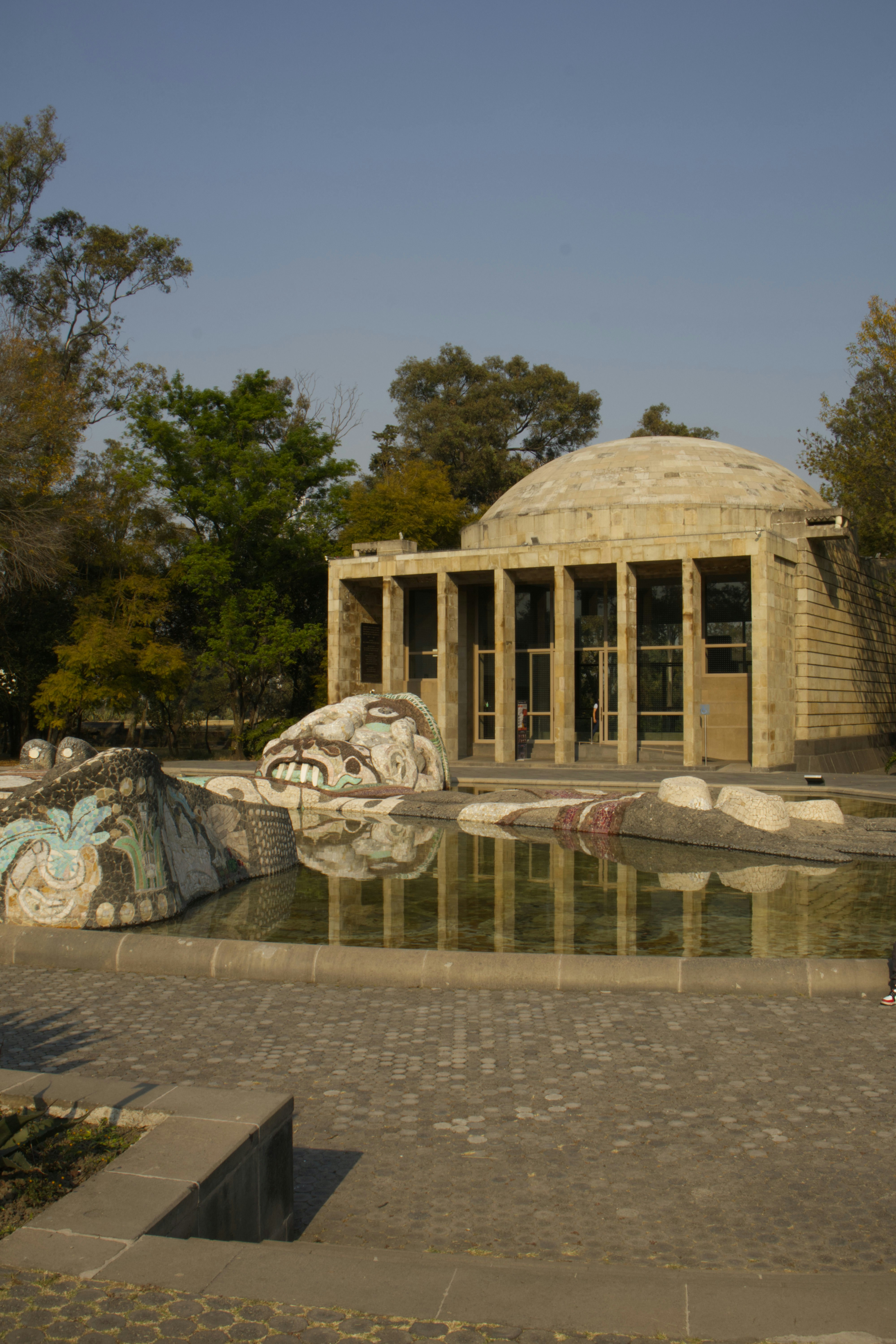 Building with dome and fountain featuring a carved stone head.
