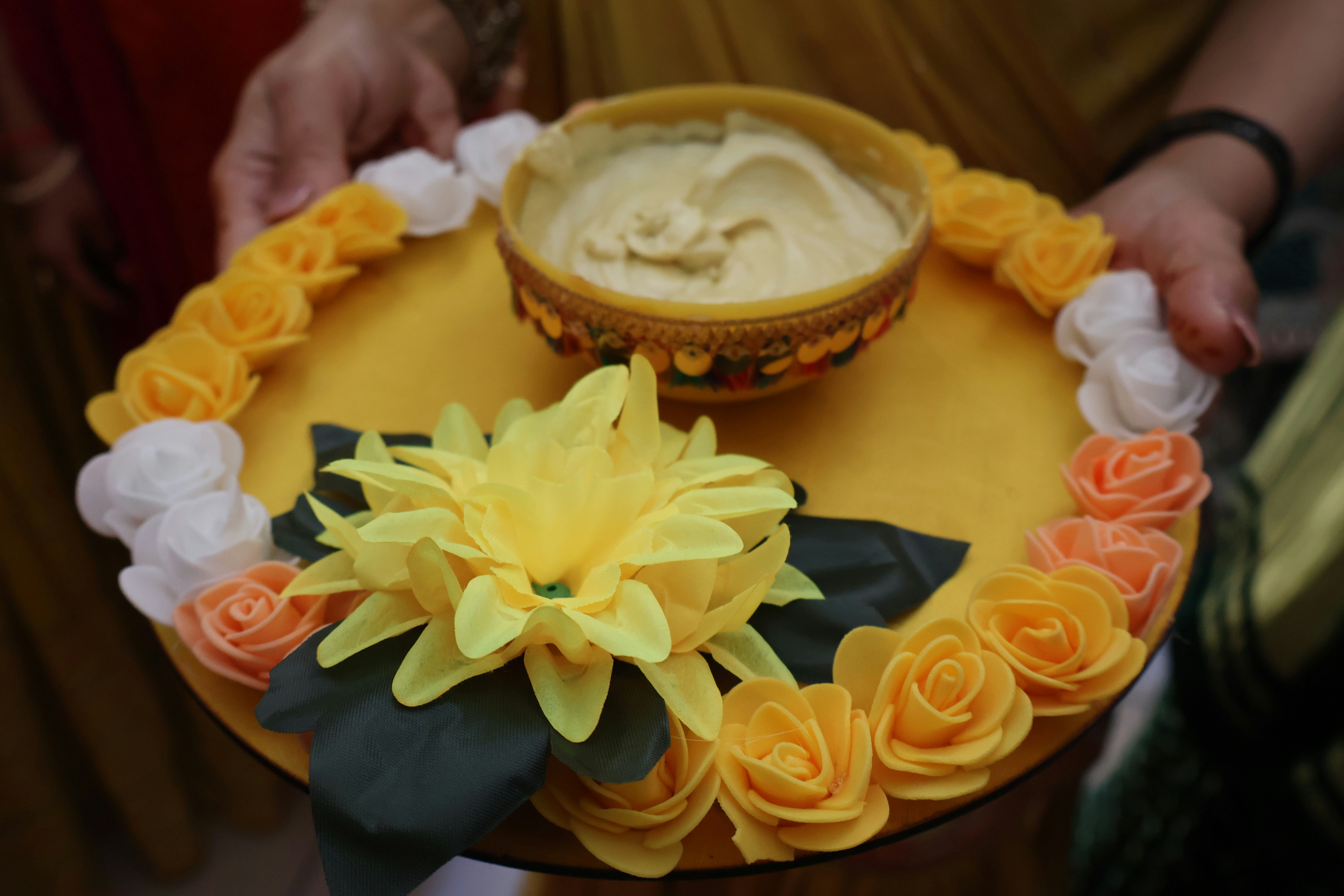 Un plateau jaune avec un bol de nourriture et de fleurs