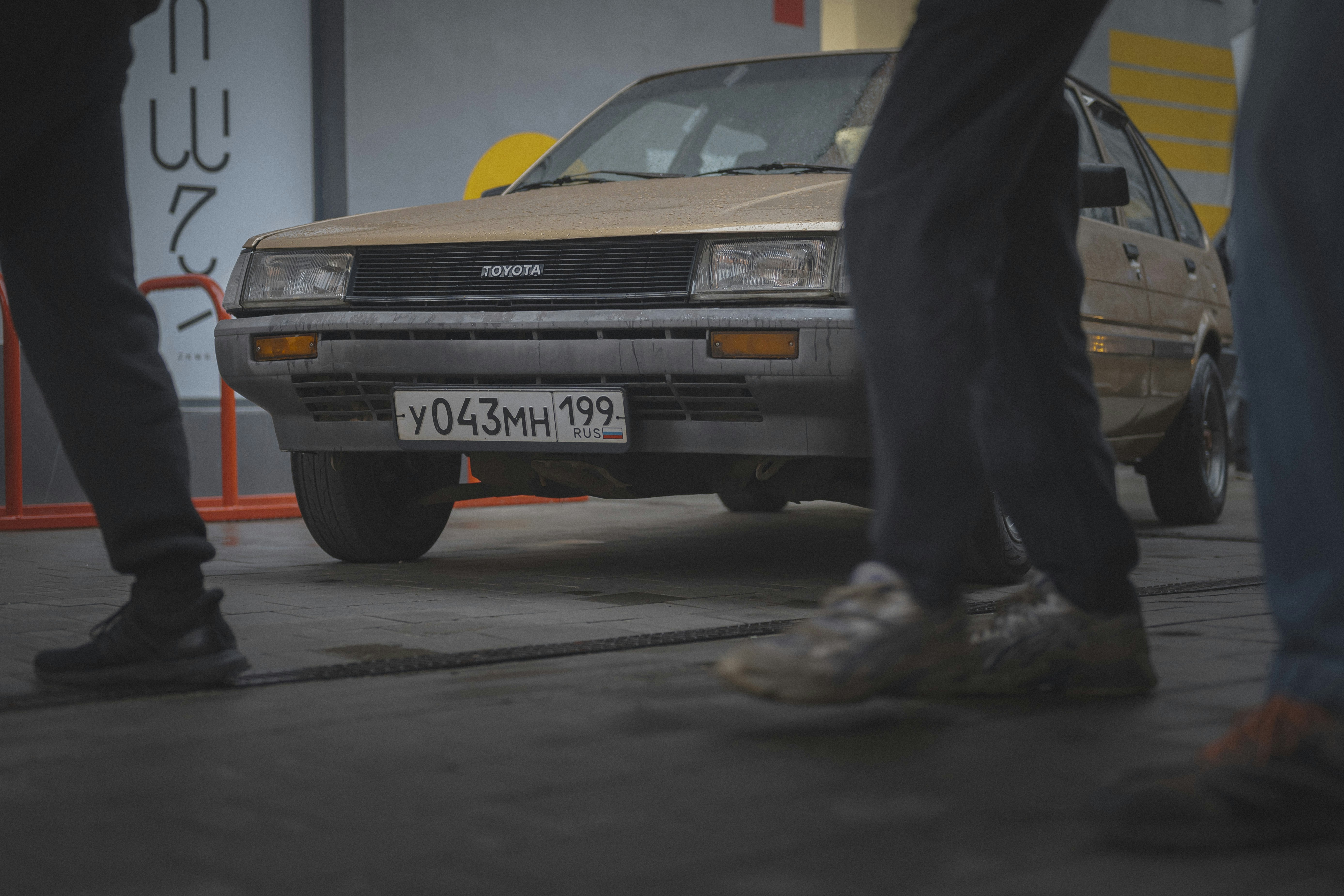 People stand near a vintage toyota car.