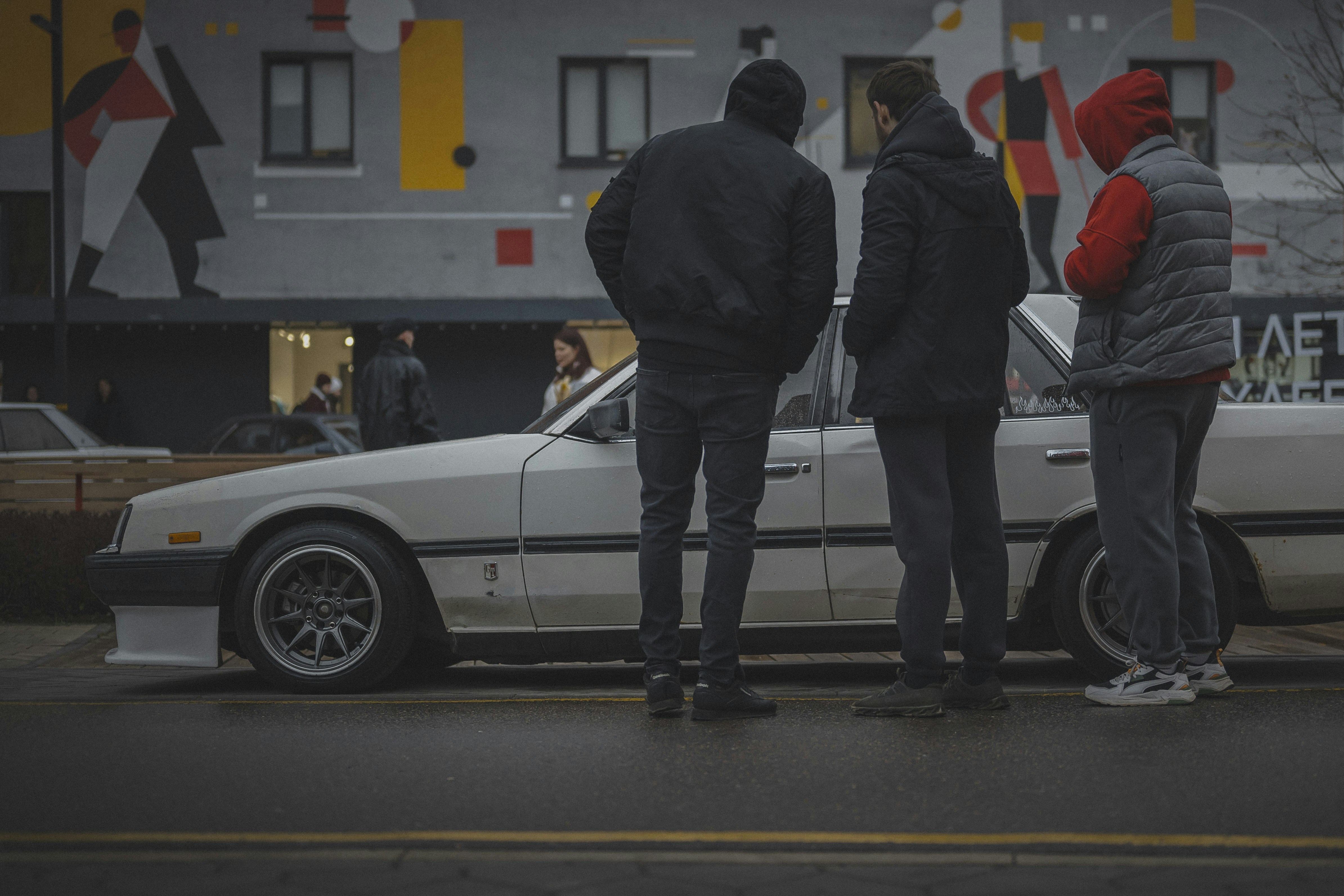 Three people stand by a white vintage car.