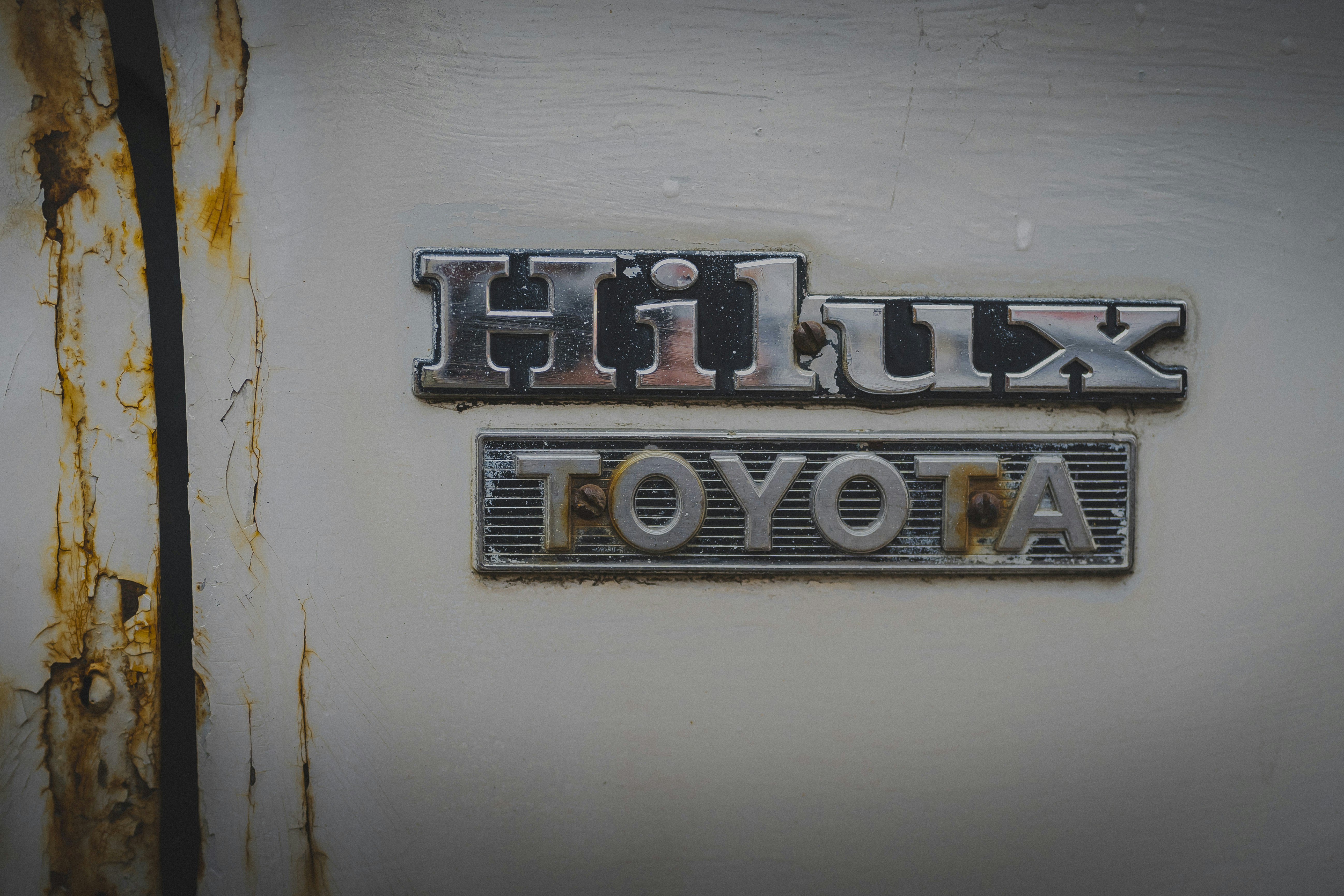Rusted toyota hilux emblem on a white surface