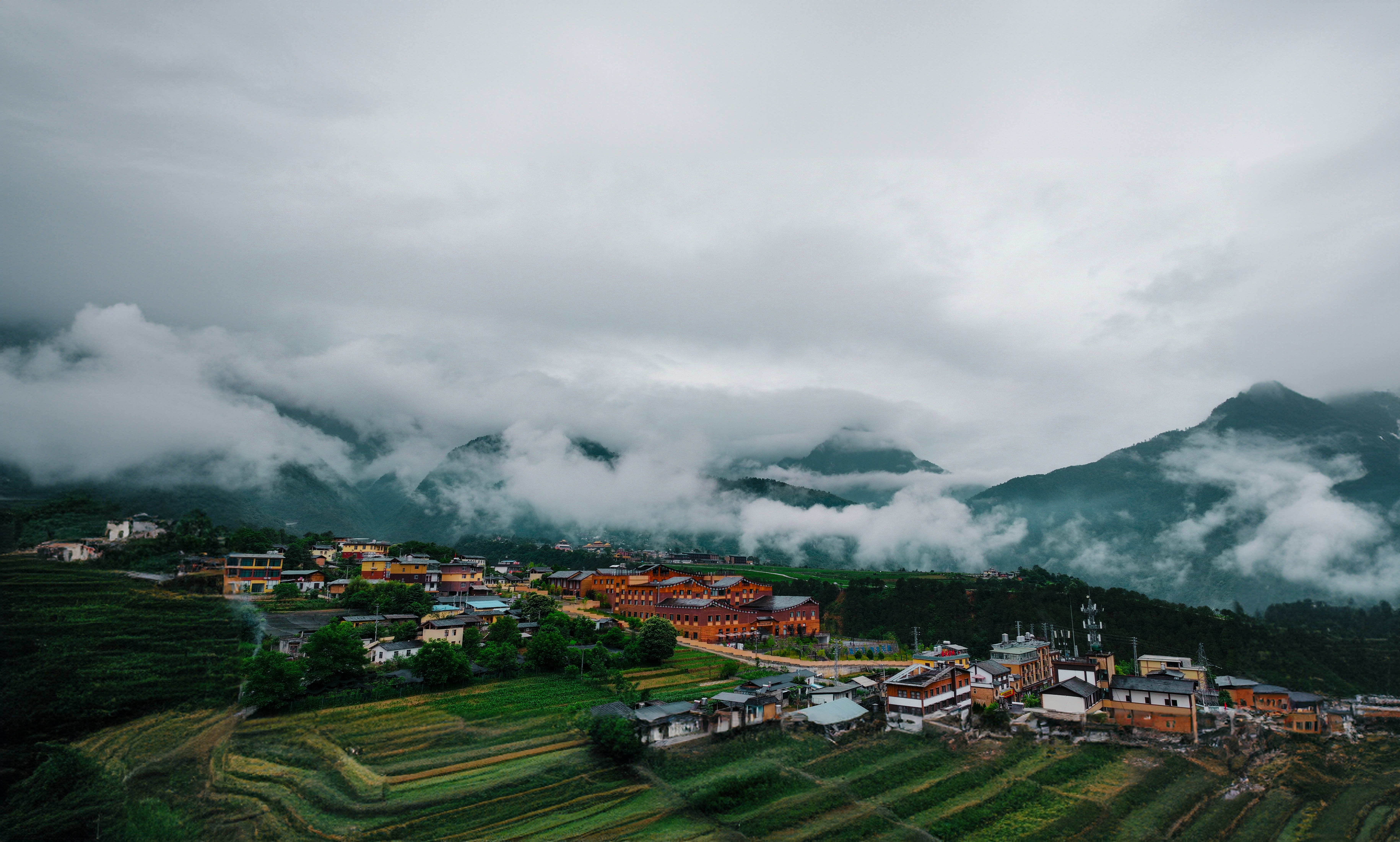 A village nestled among misty mountains and terraced fields.