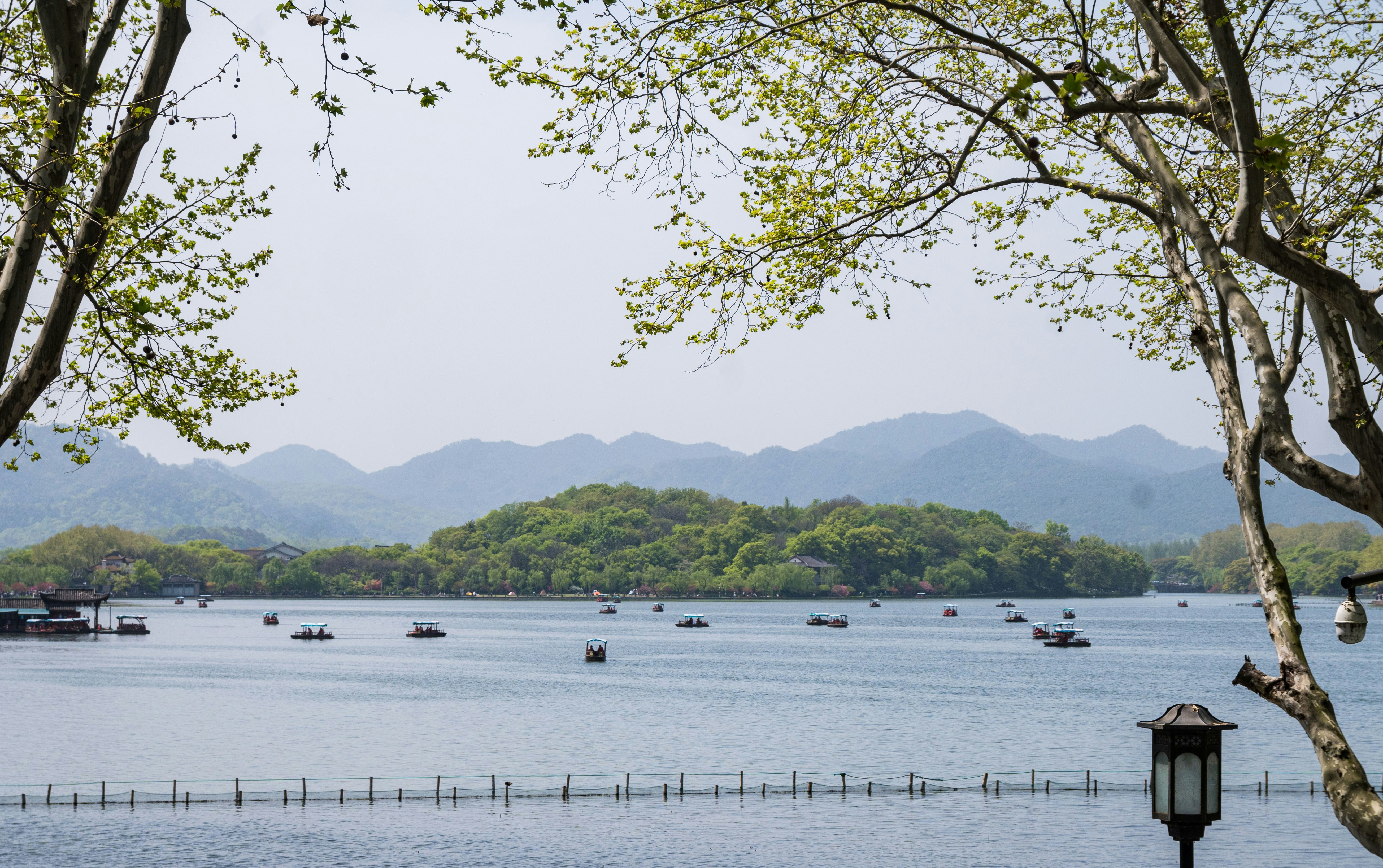Boats on a calm lake with green hills in background.