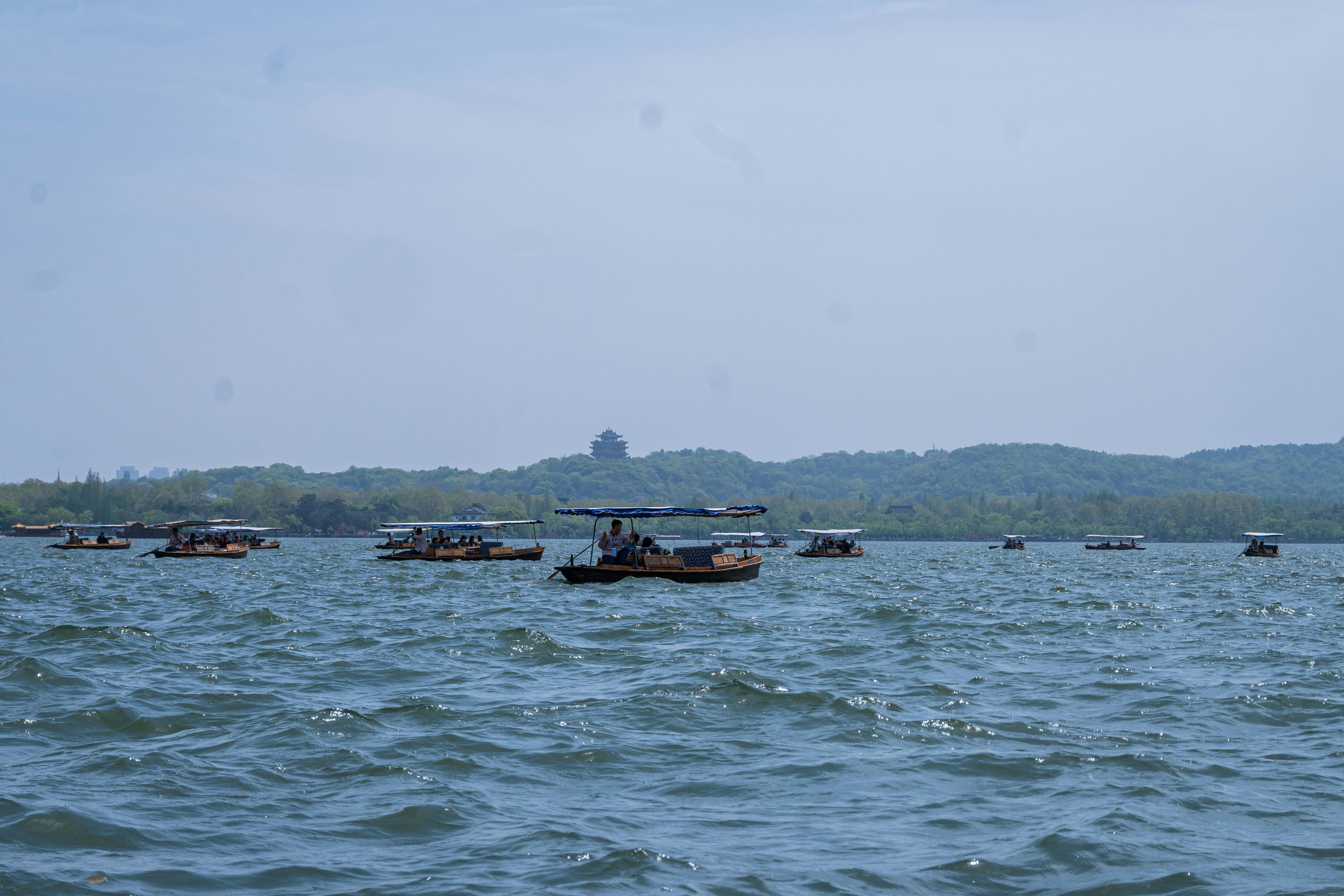 Boats floating on a calm lake with distant hills