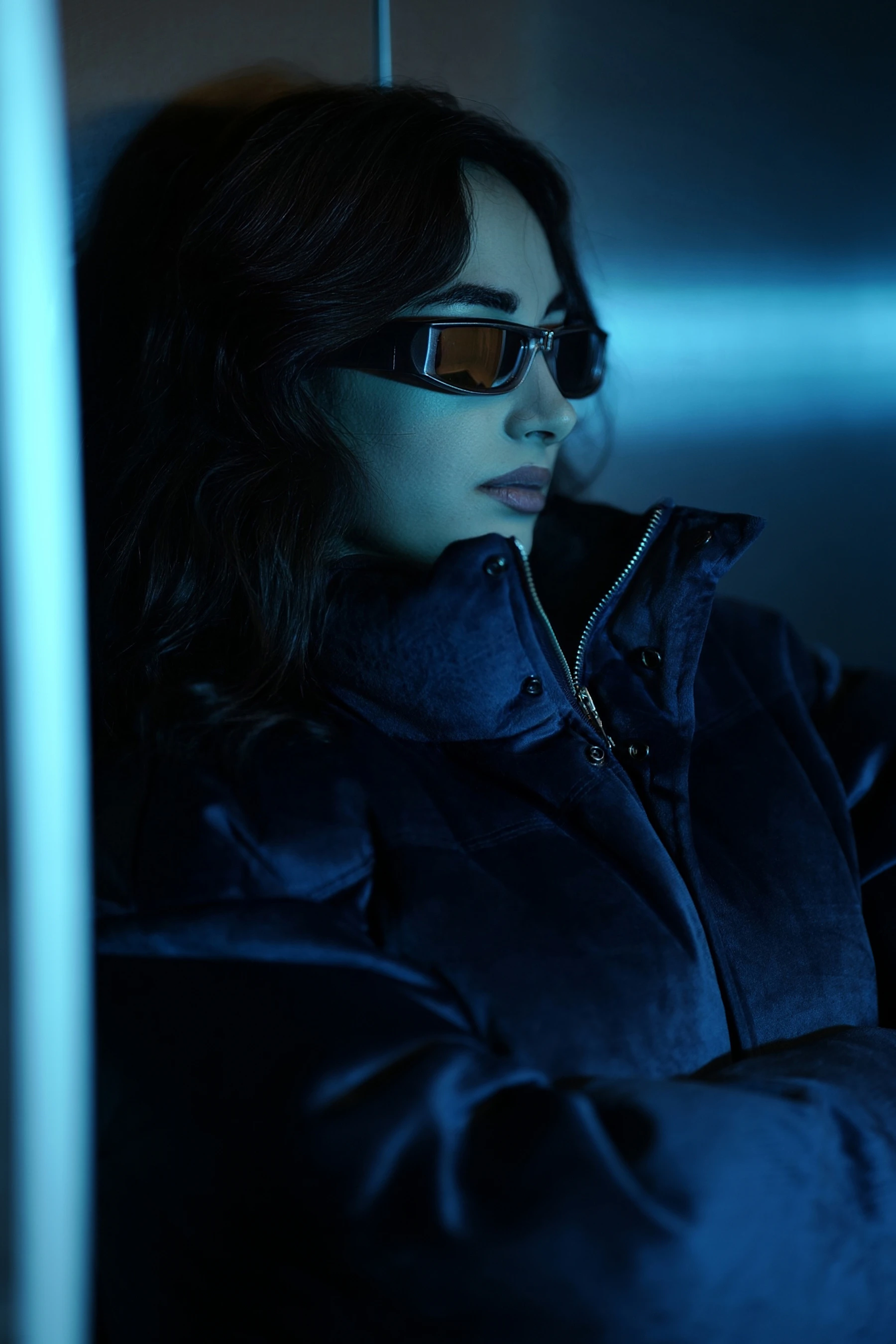 Woman wearing narrow sunglasses in cinematic blue light