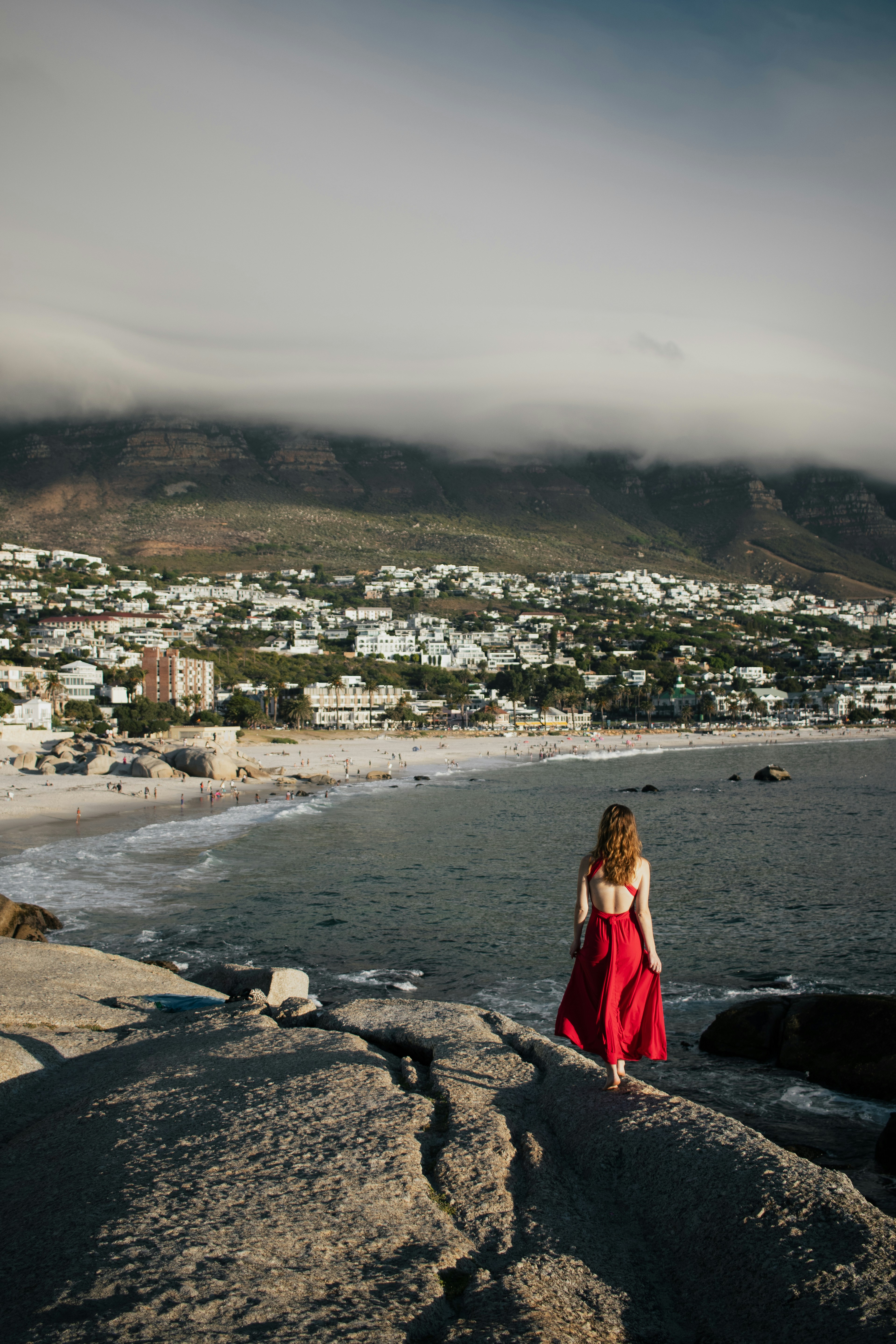 Woman in red dress overlooking coastal town and ocean