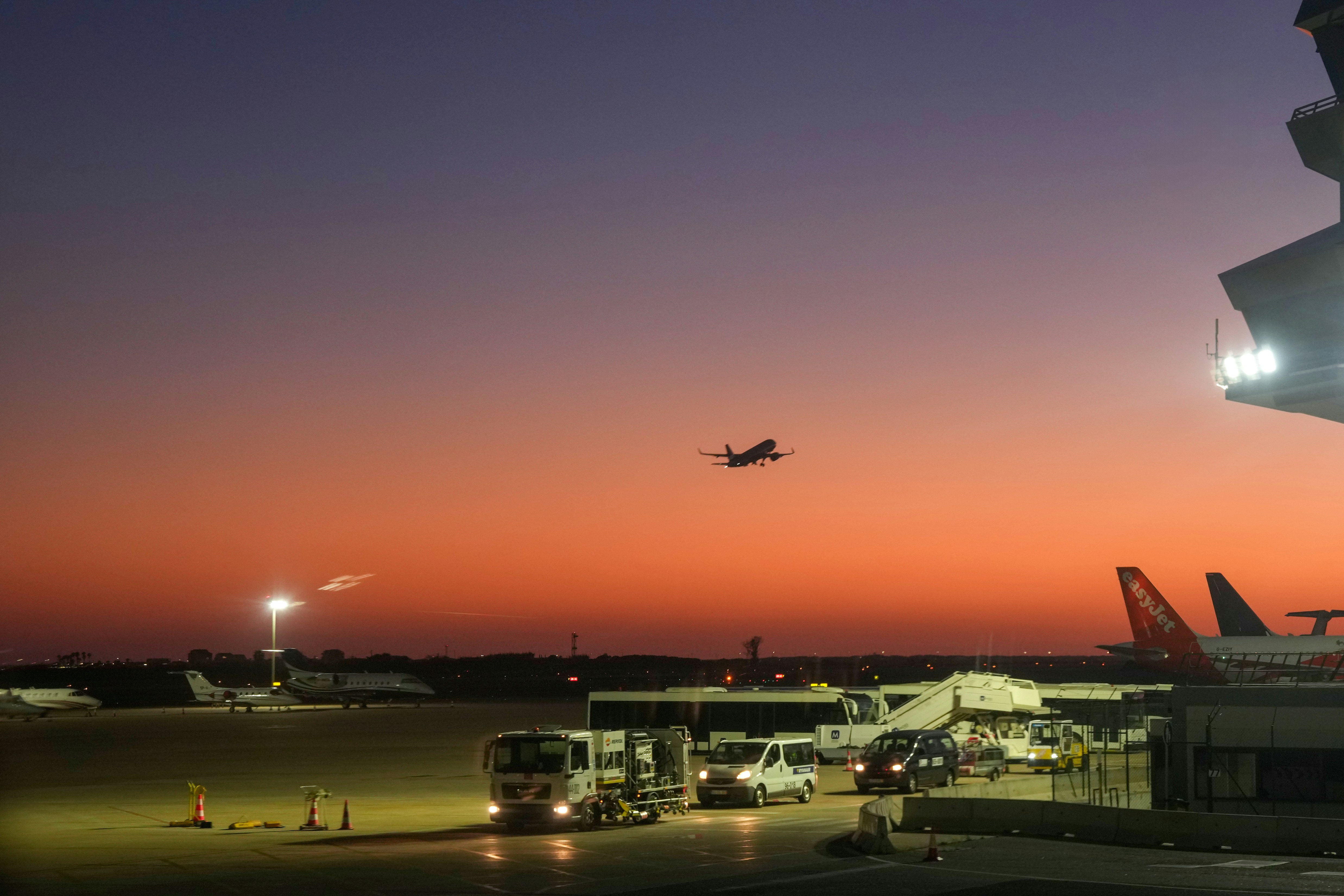 Airplane taking off at sunset over airport tarmac