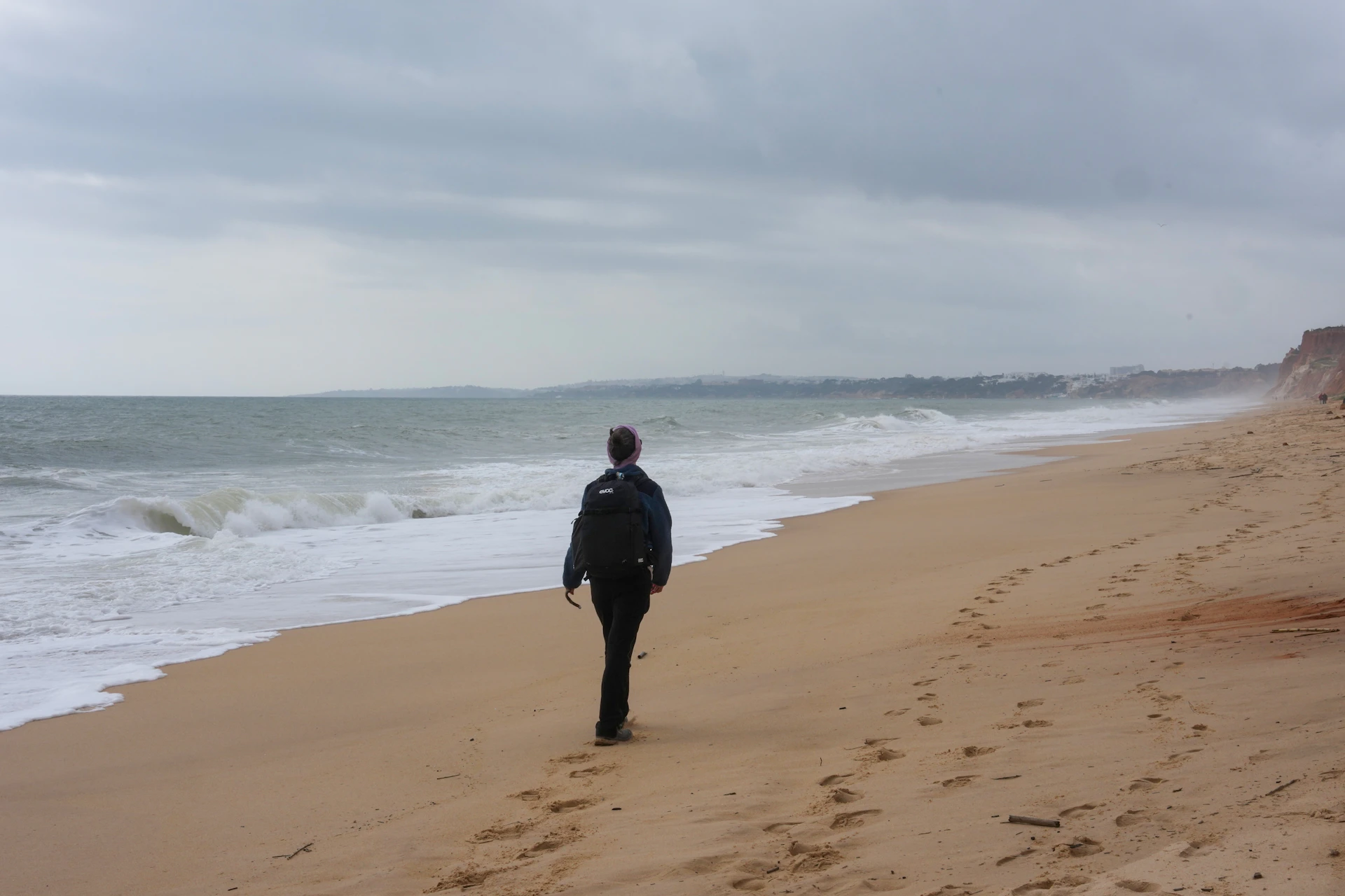 Person walking on a sandy beach by the ocean
