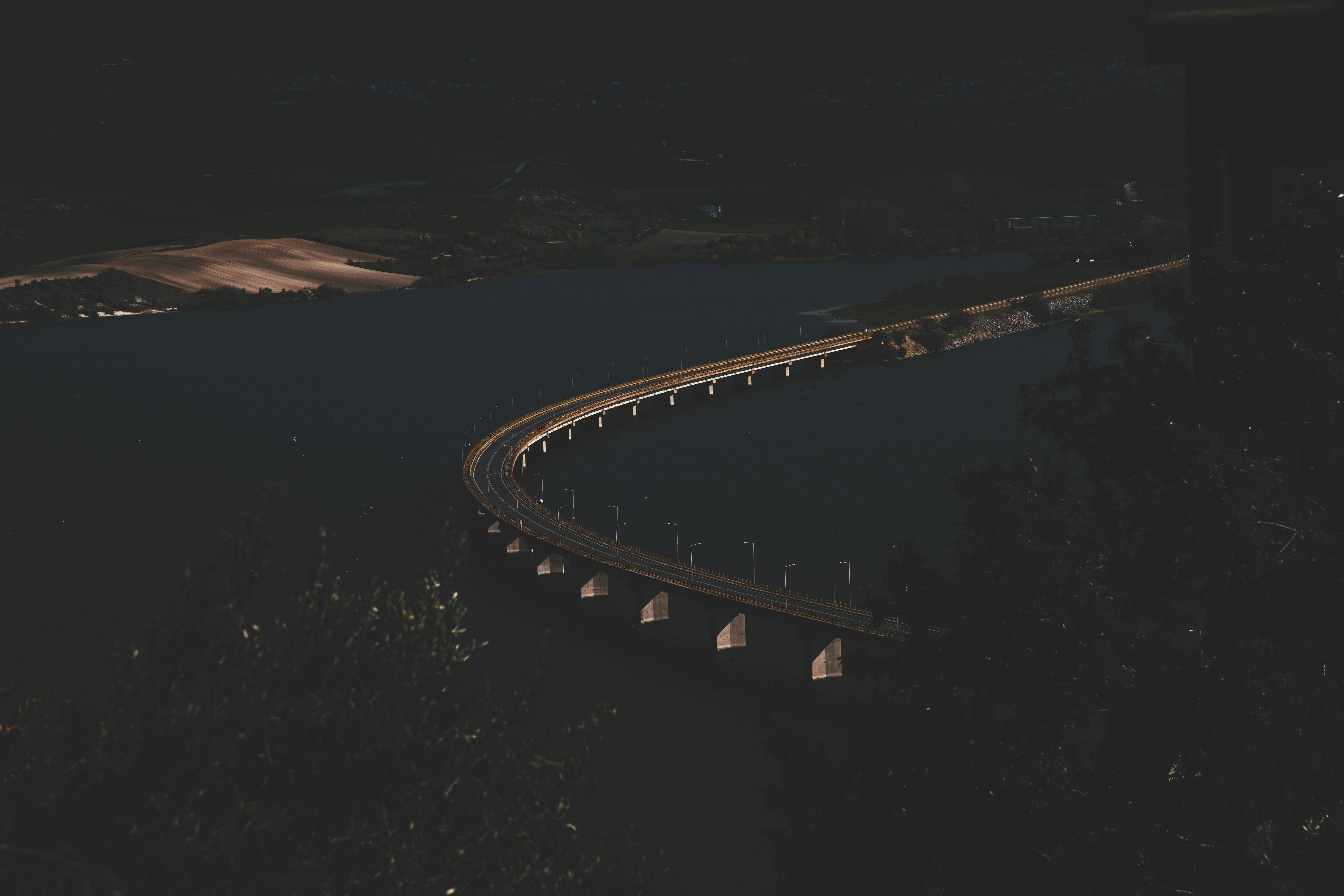 Long bridge over dark water at night