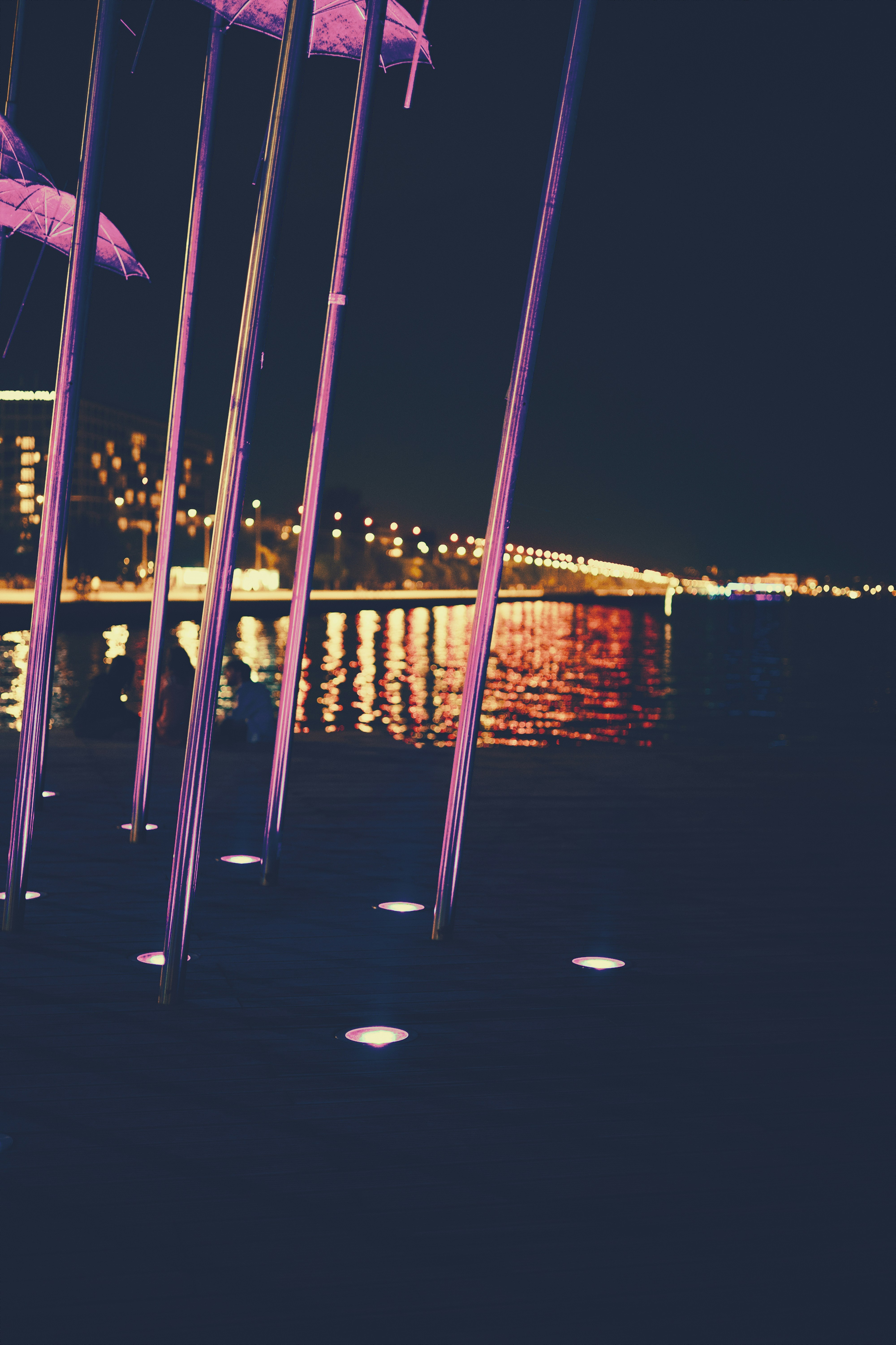 Purple lights illuminate a waterfront at night.