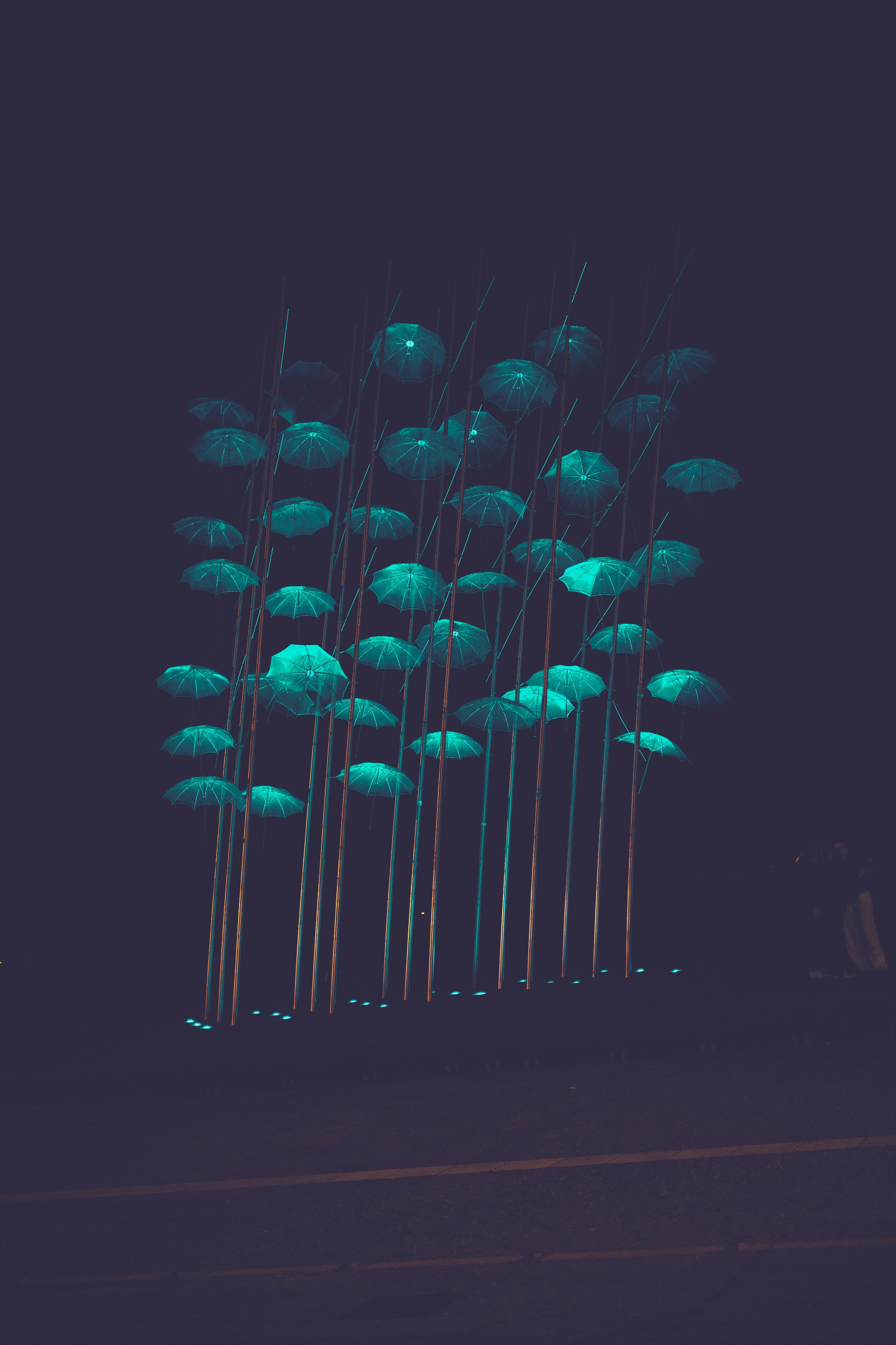 Glowing blue umbrellas suspended in dark night