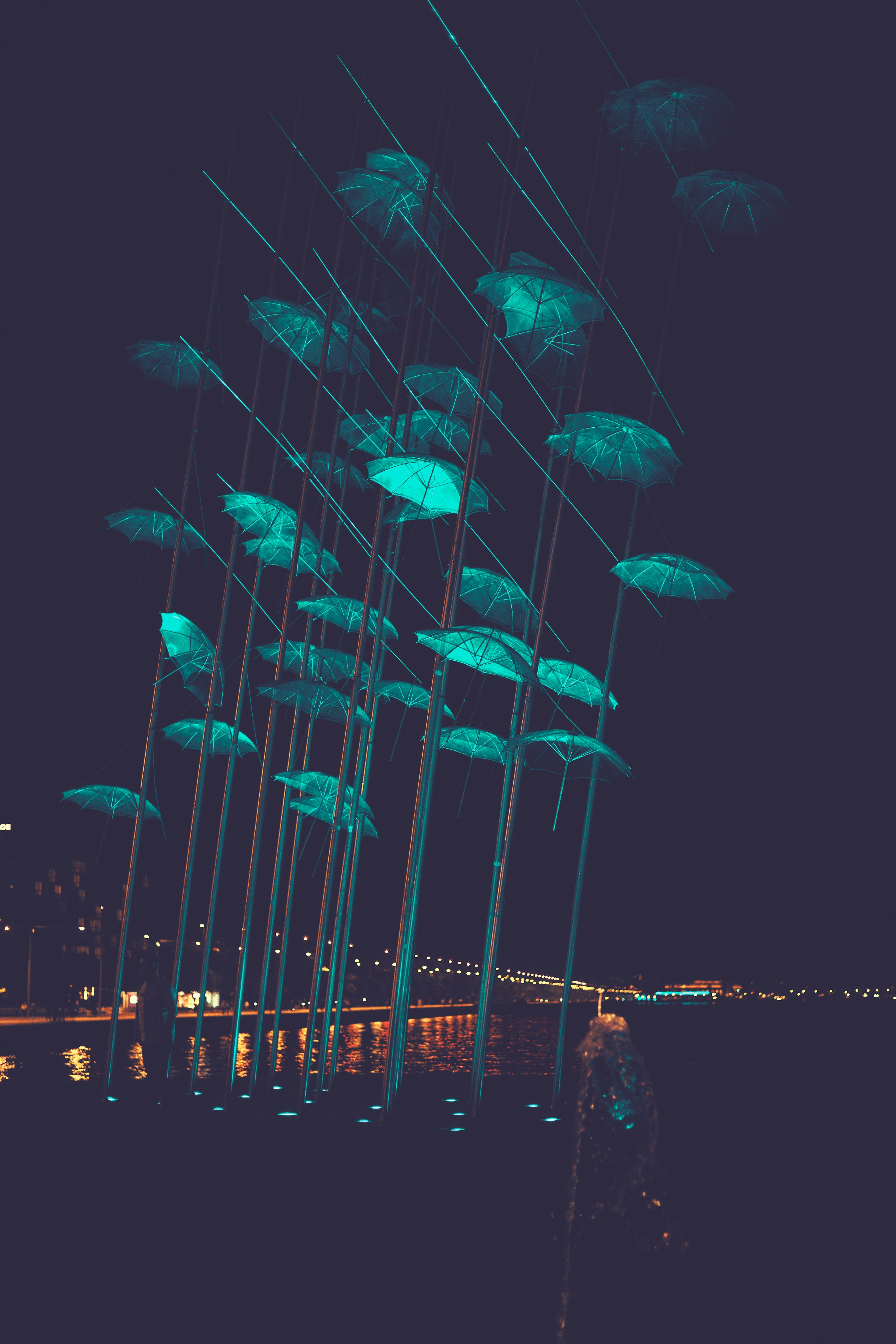 Glowing umbrellas suspended at night over water