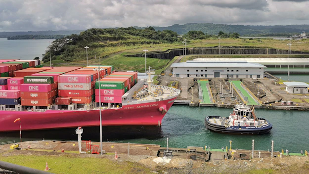 Container ship being guided by tugboat in canal