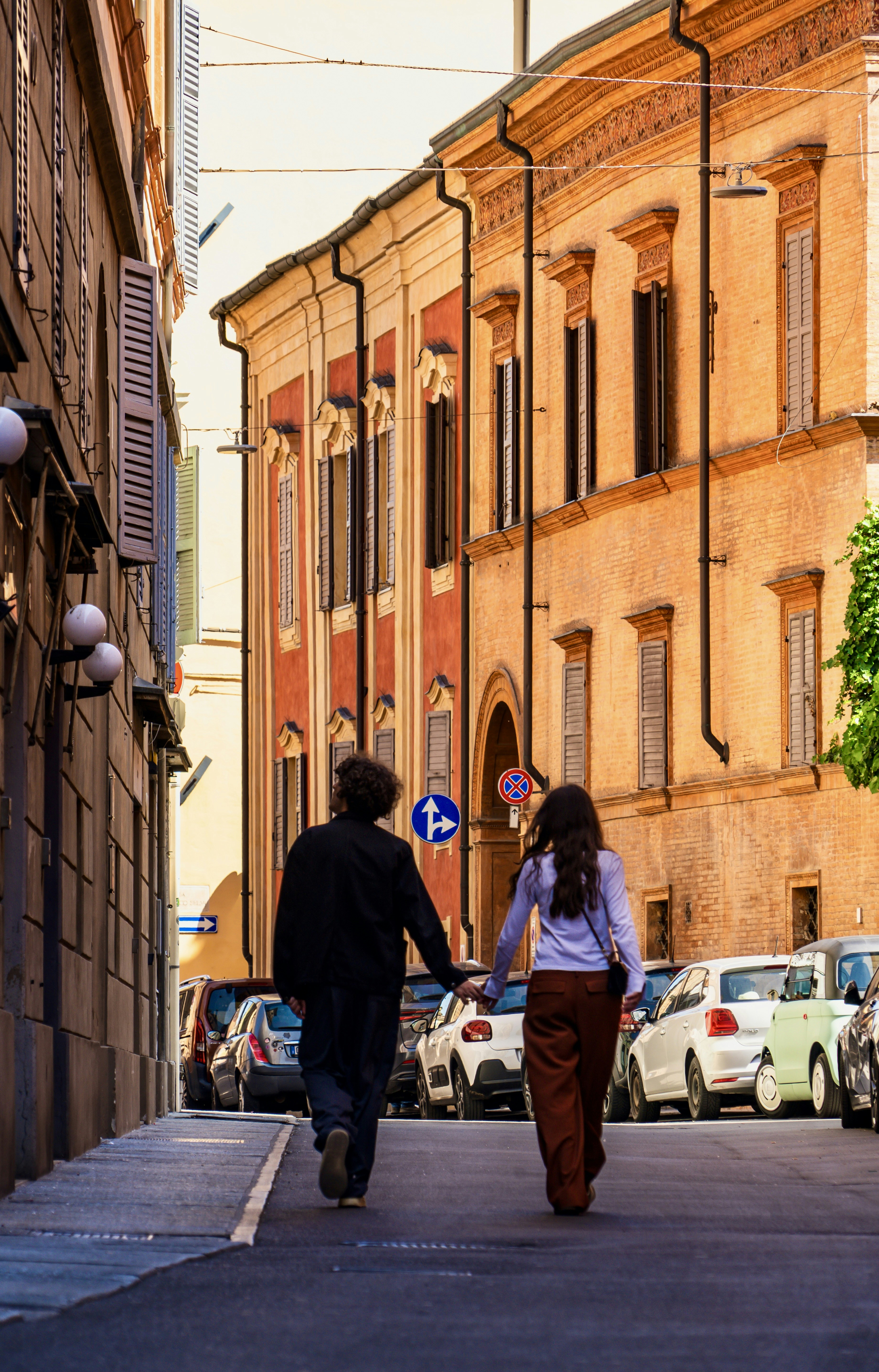 Couple holding hands walking down european street.