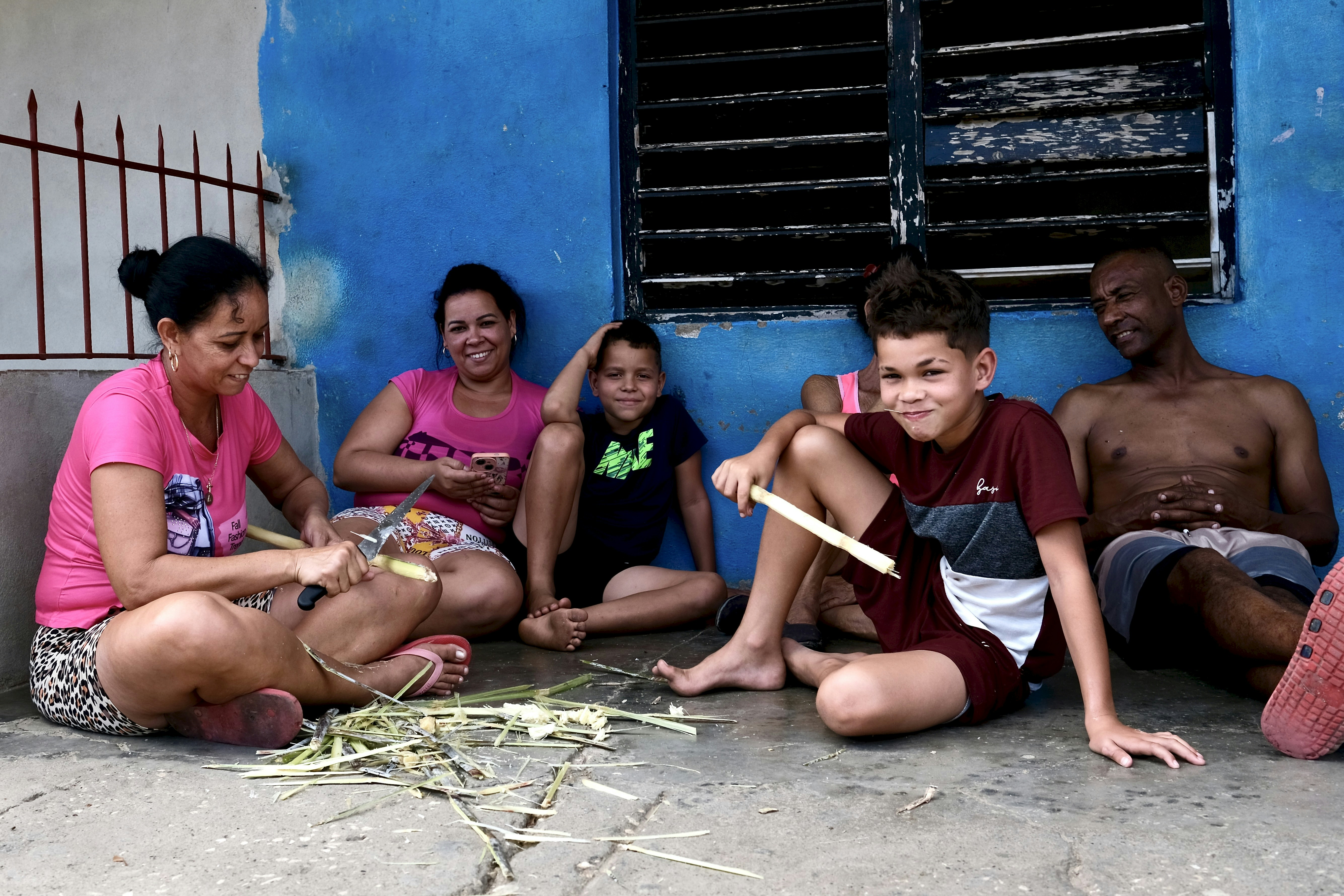 Family sitting together on the ground outside.