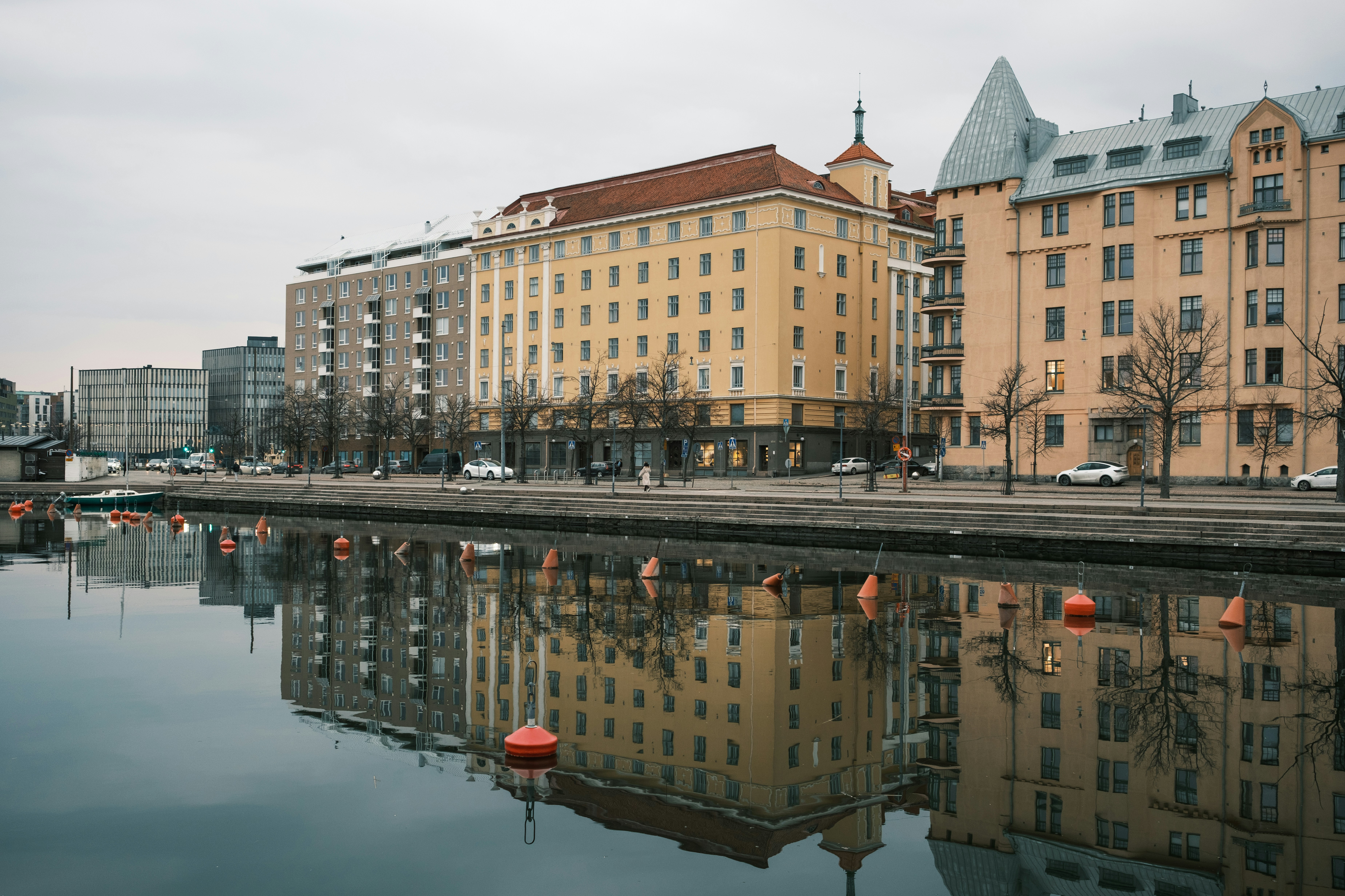 Los edificios se reflejaban en aguas tranquilas con boyas naranjas.