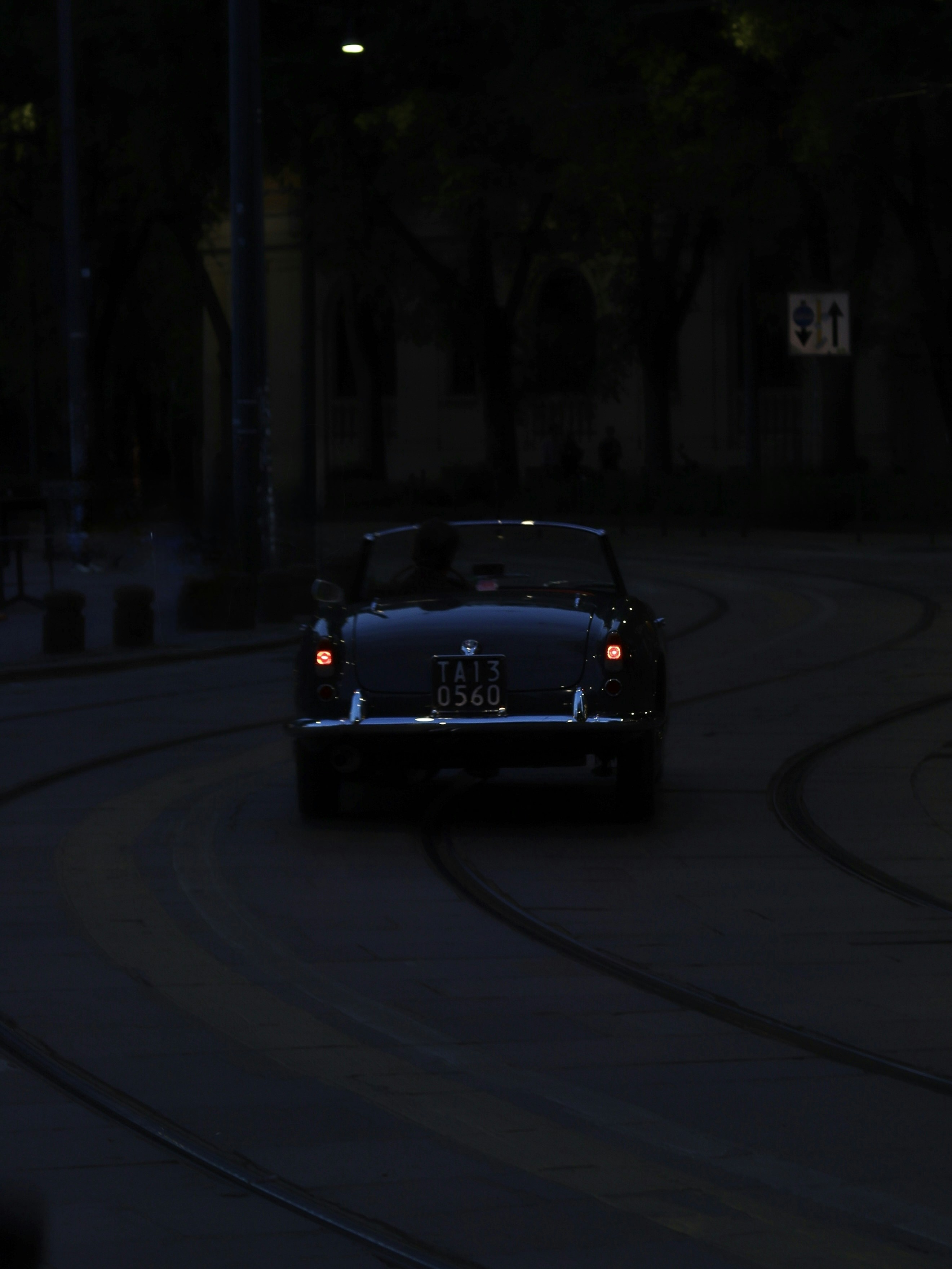 Um carro antigo anda por uma rua escura.