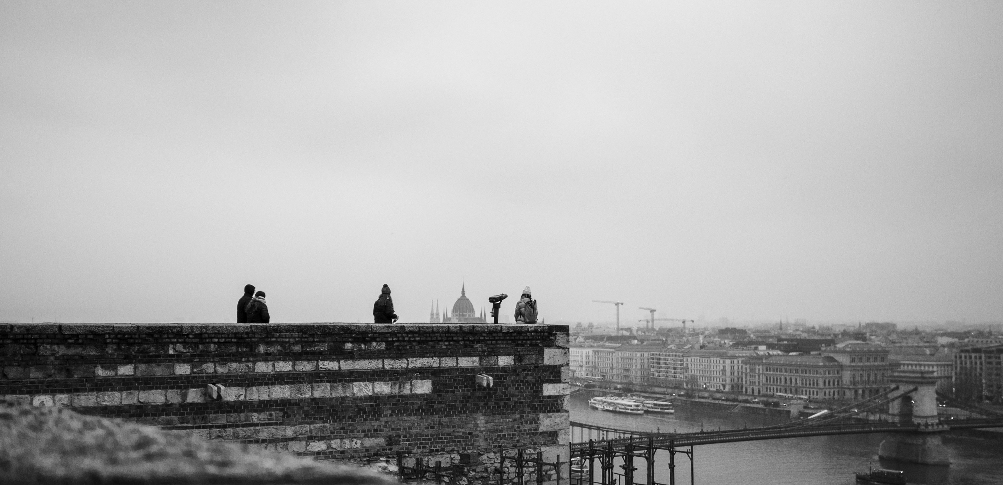 Silhouettes of people on a rooftop overlooking a city