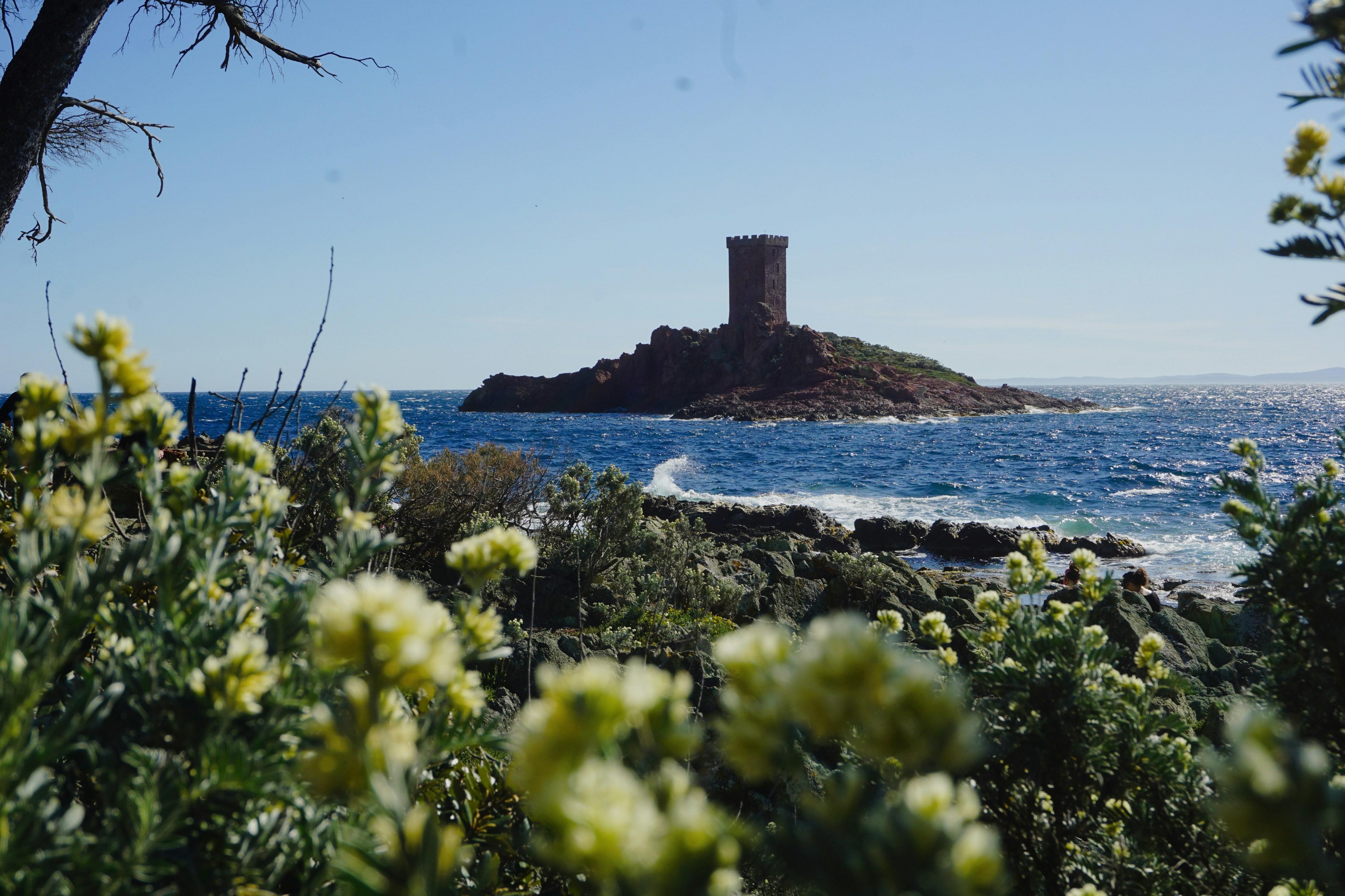 Uma torre de pedra em uma ilha rochosa no mar.