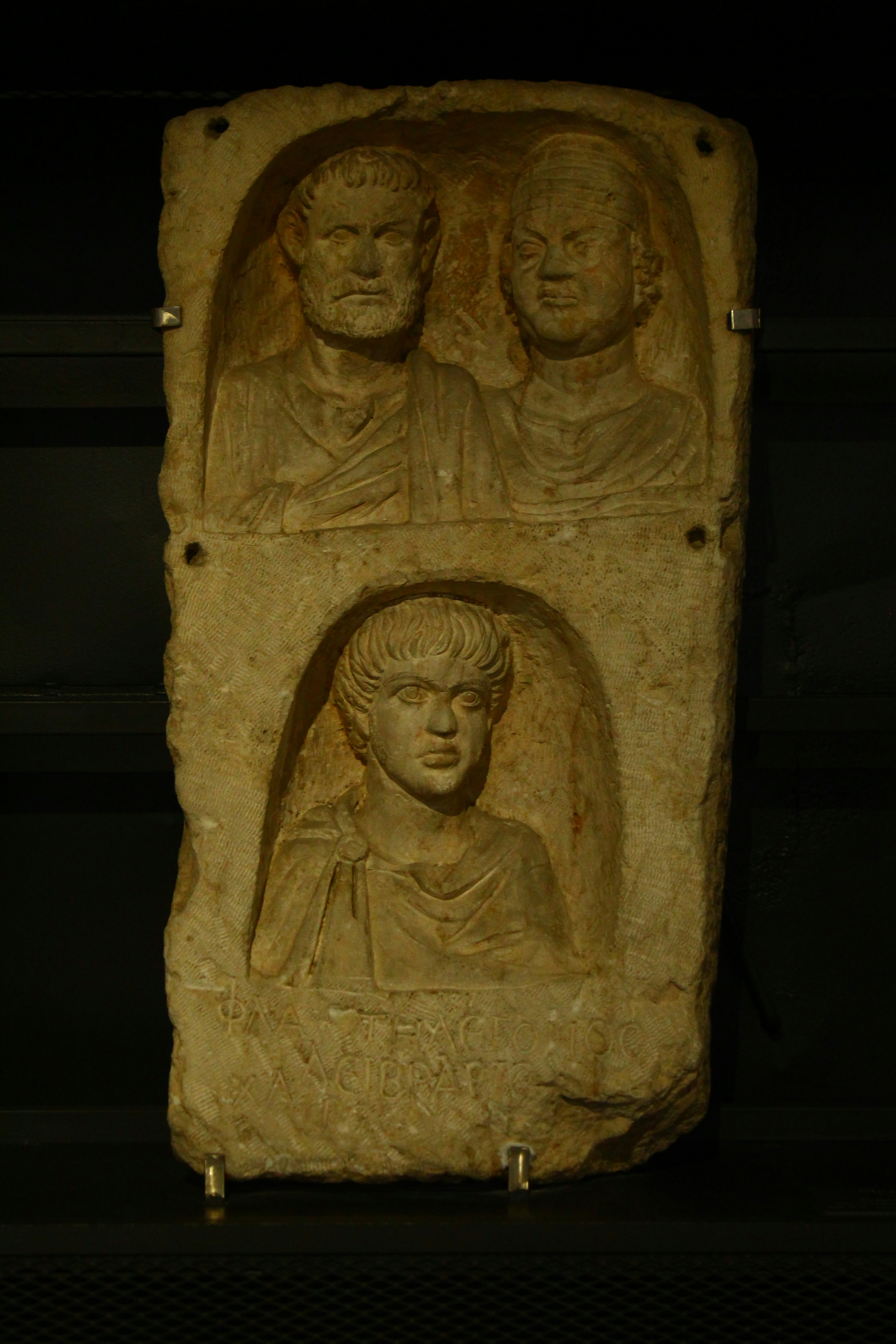Ancient stone relief with three carved portraits