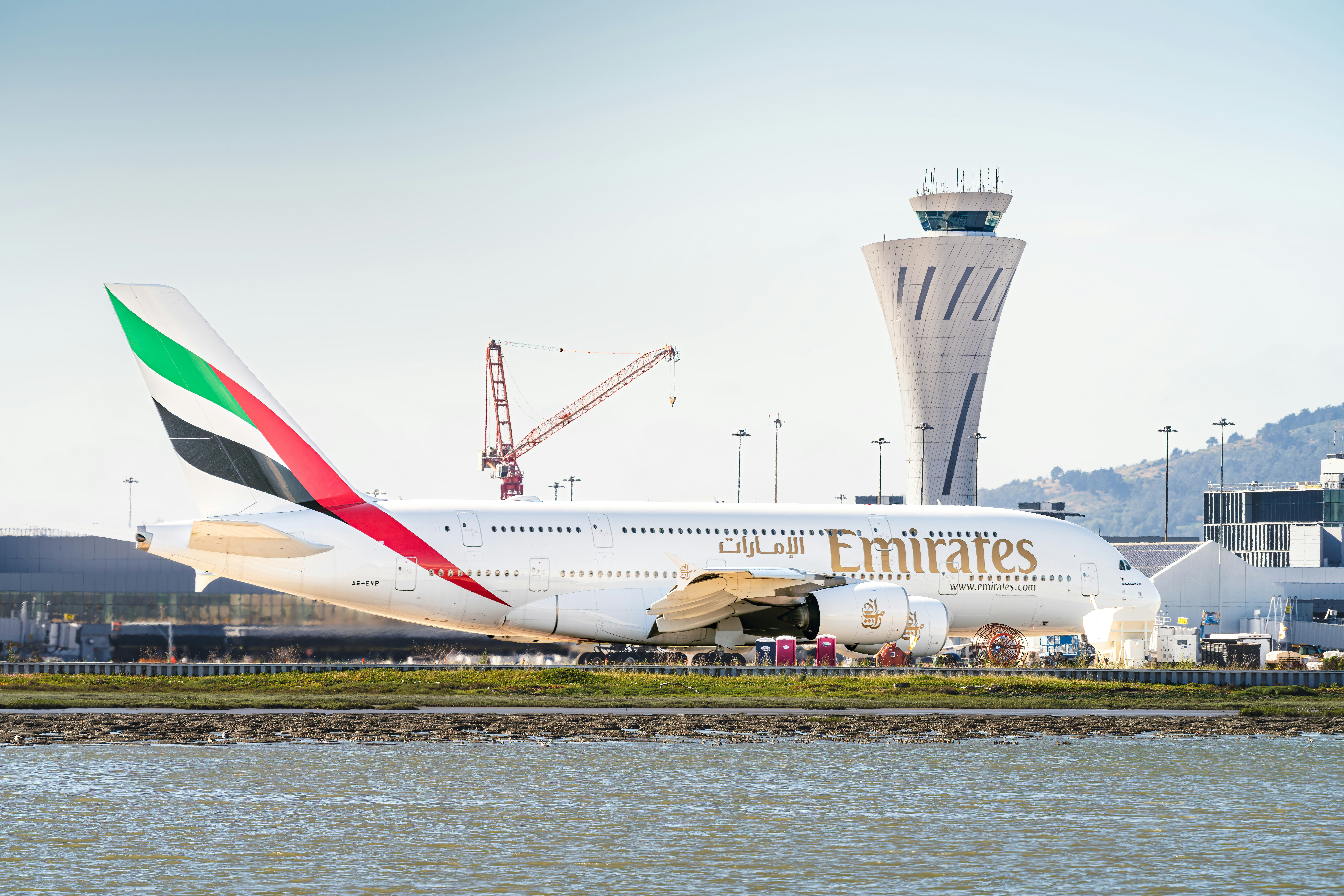 Emirates airplane parked at the airport with control tower