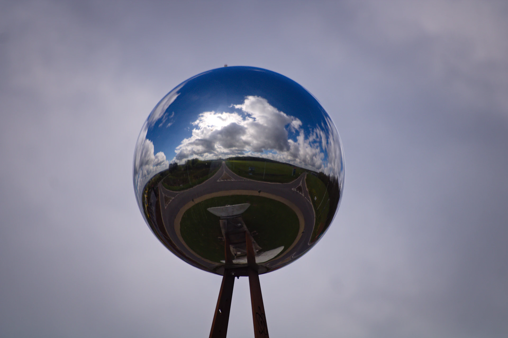 Reflective sphere mirrors cloudy sky and landscape below ground