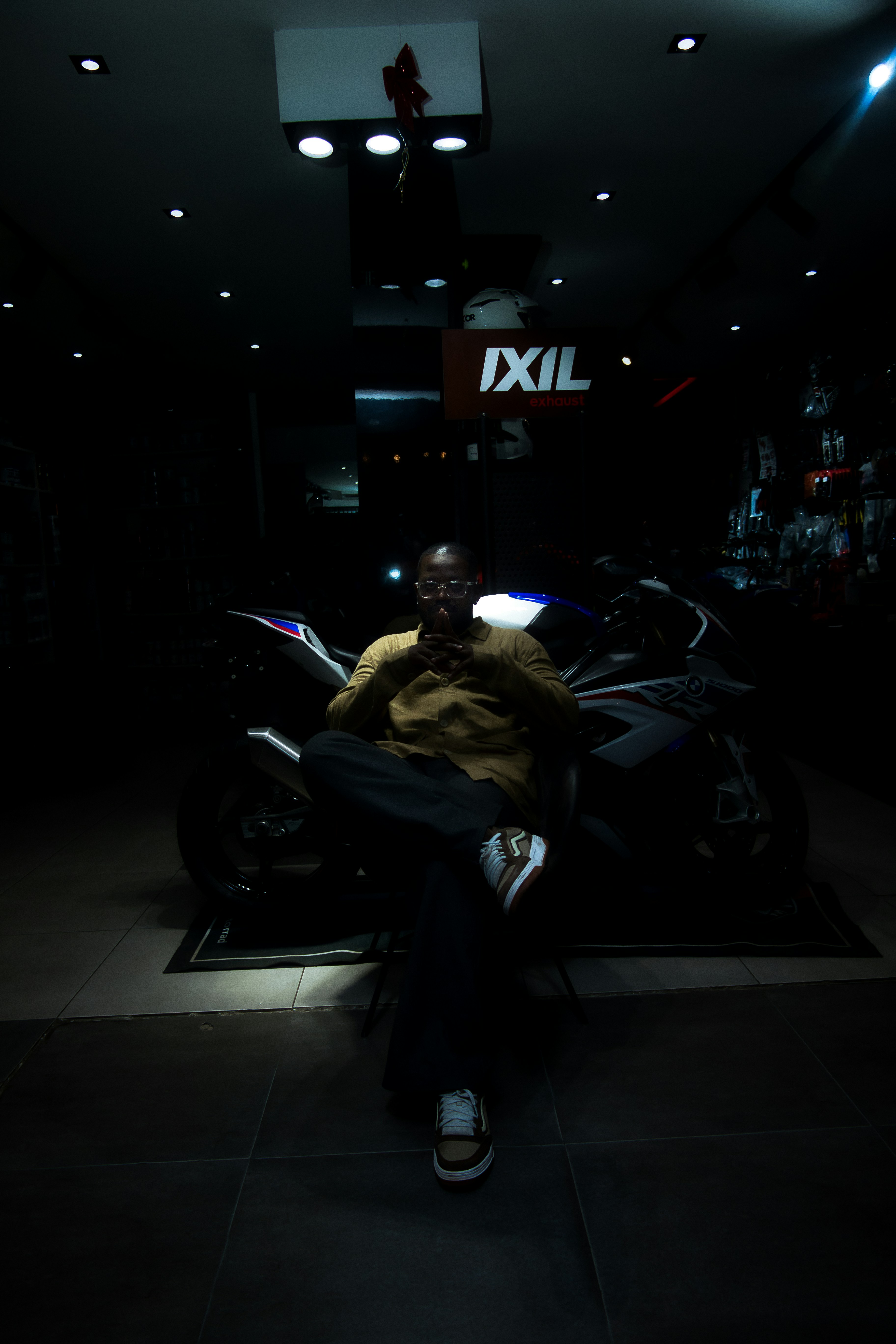 Man sitting in front of a motorcycle indoors.