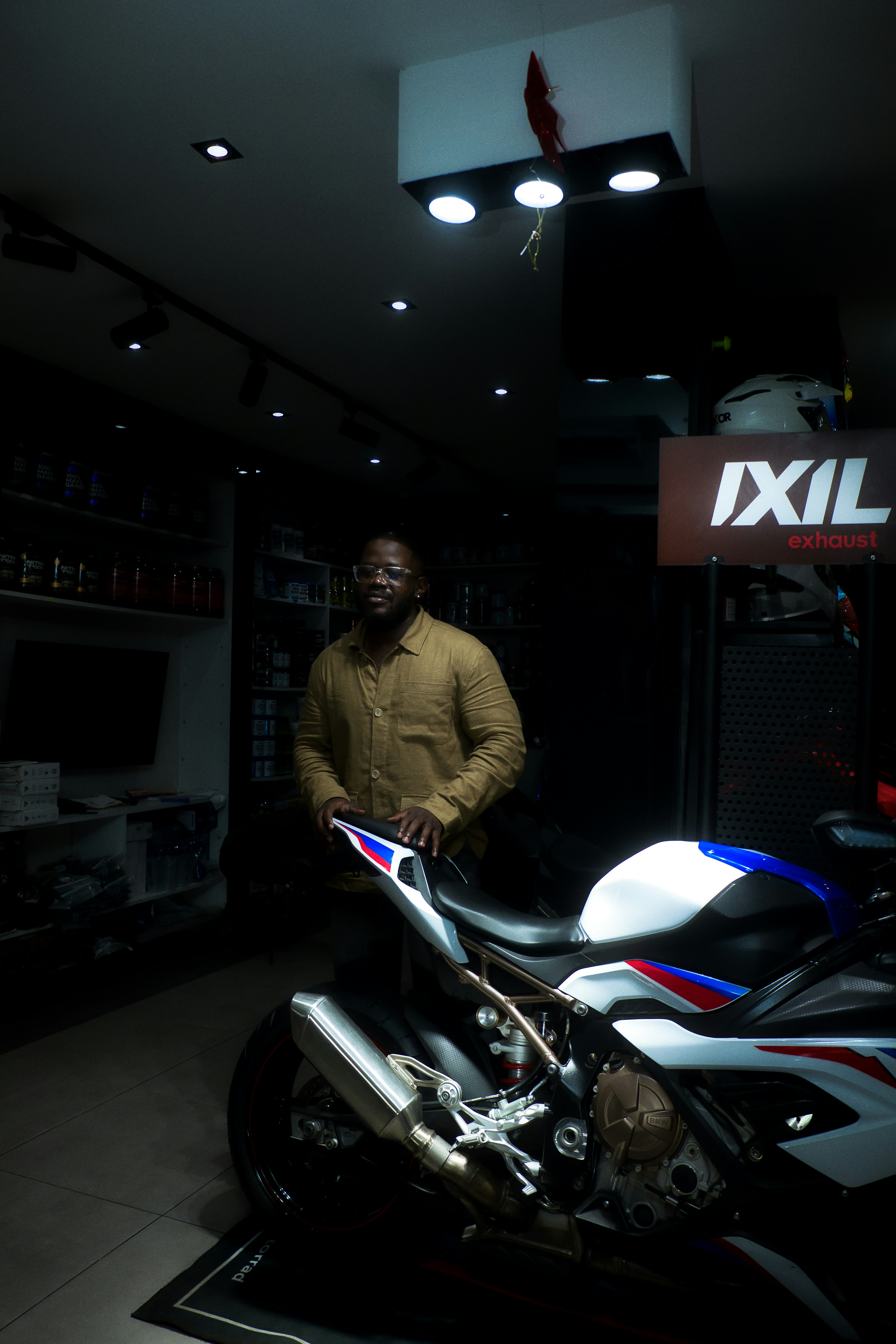 Man standing next to a sports motorcycle indoors.