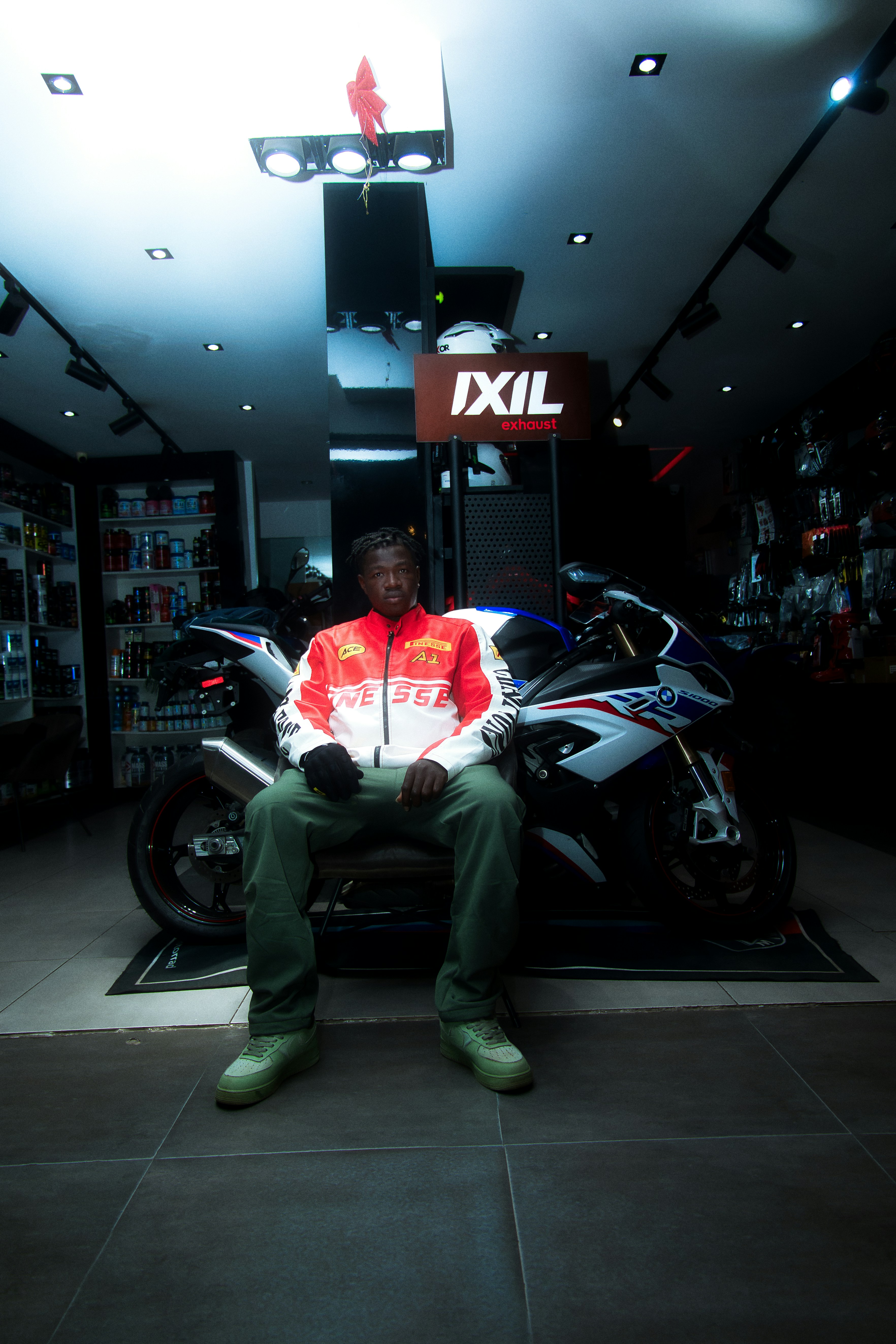 Man in jacket sits on a motorcycle in a shop.