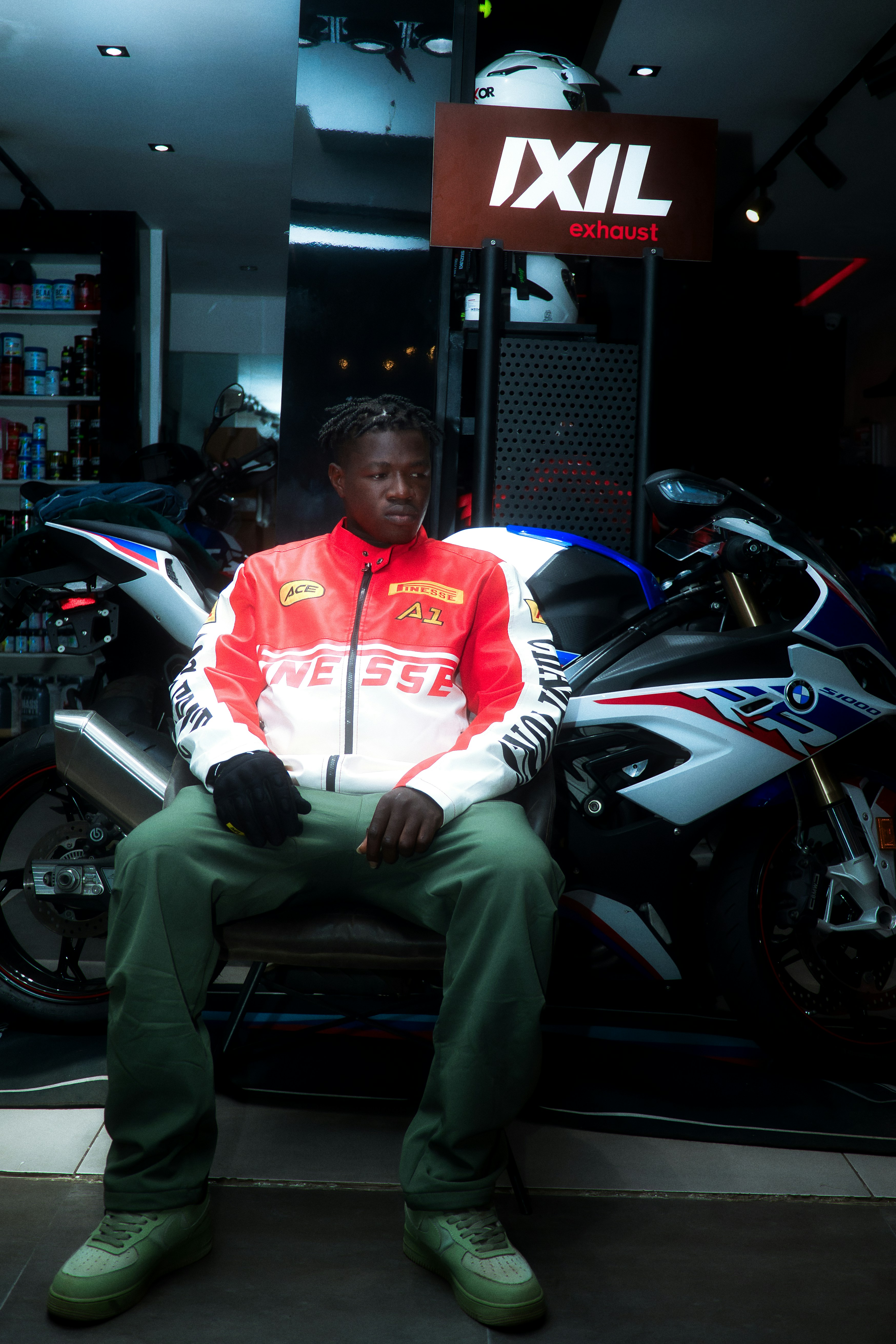Young man in racing jacket sits by motorcycle