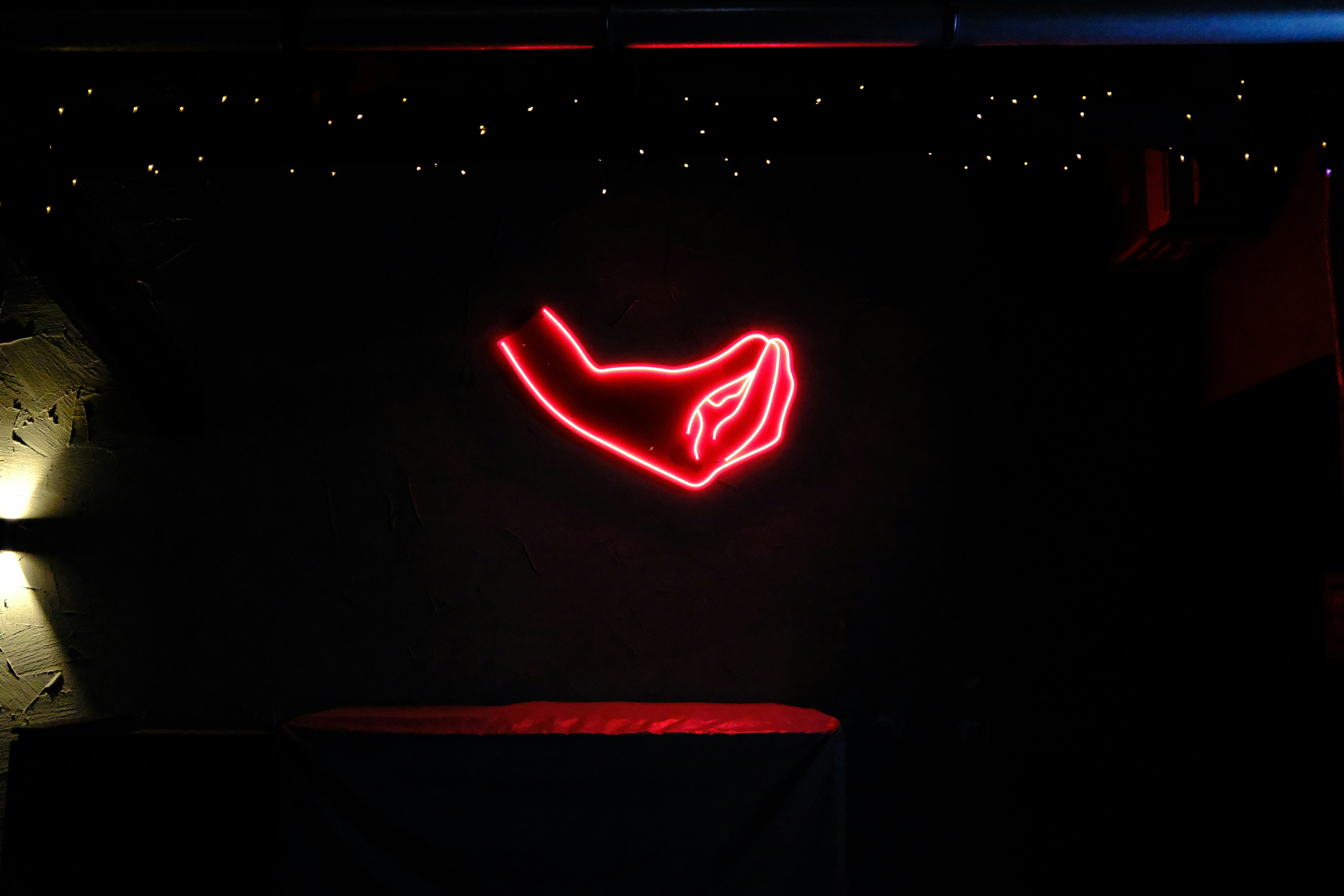 Red neon hand sign glows in dark room