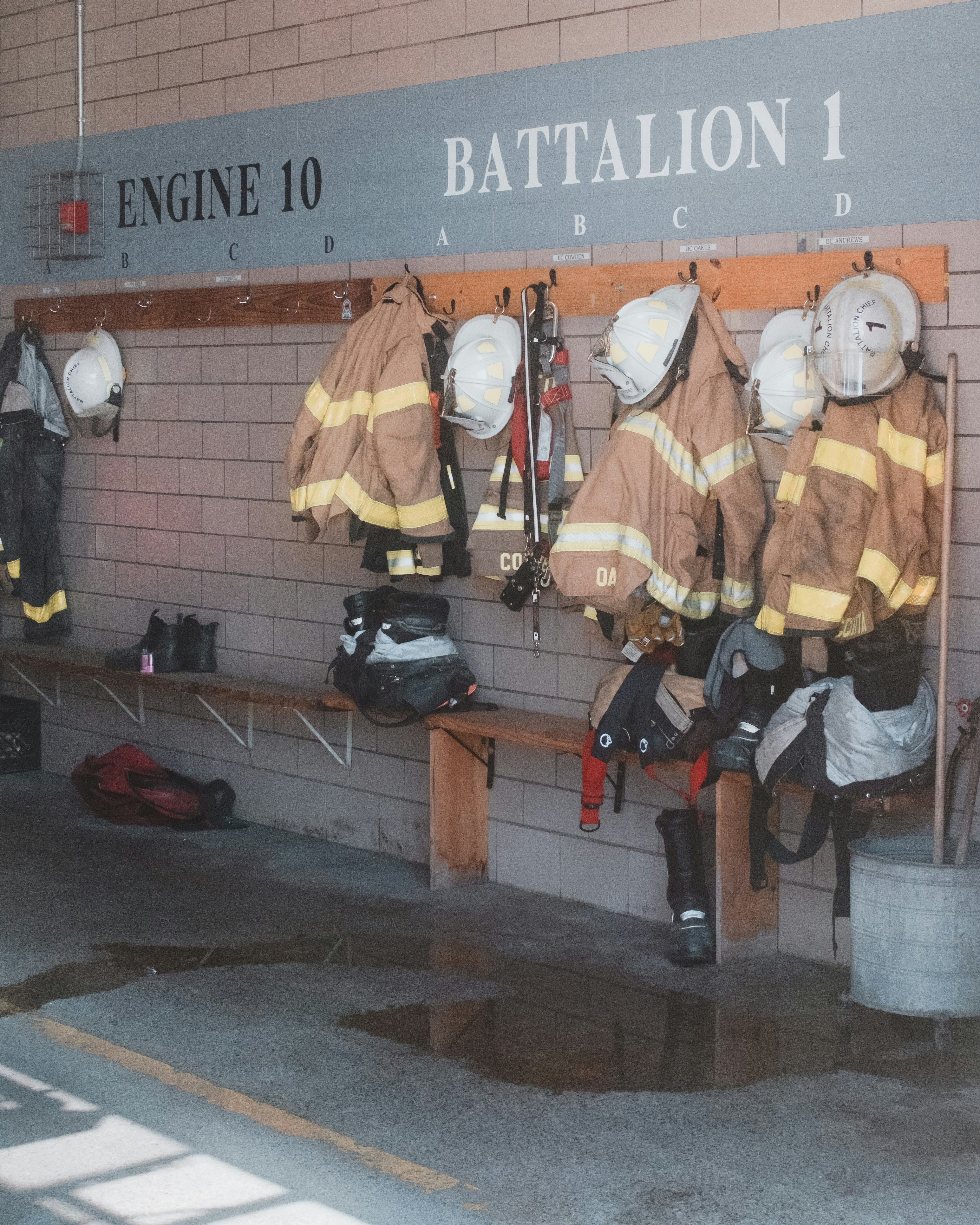 Firefighter gear hangs on hooks in a station.