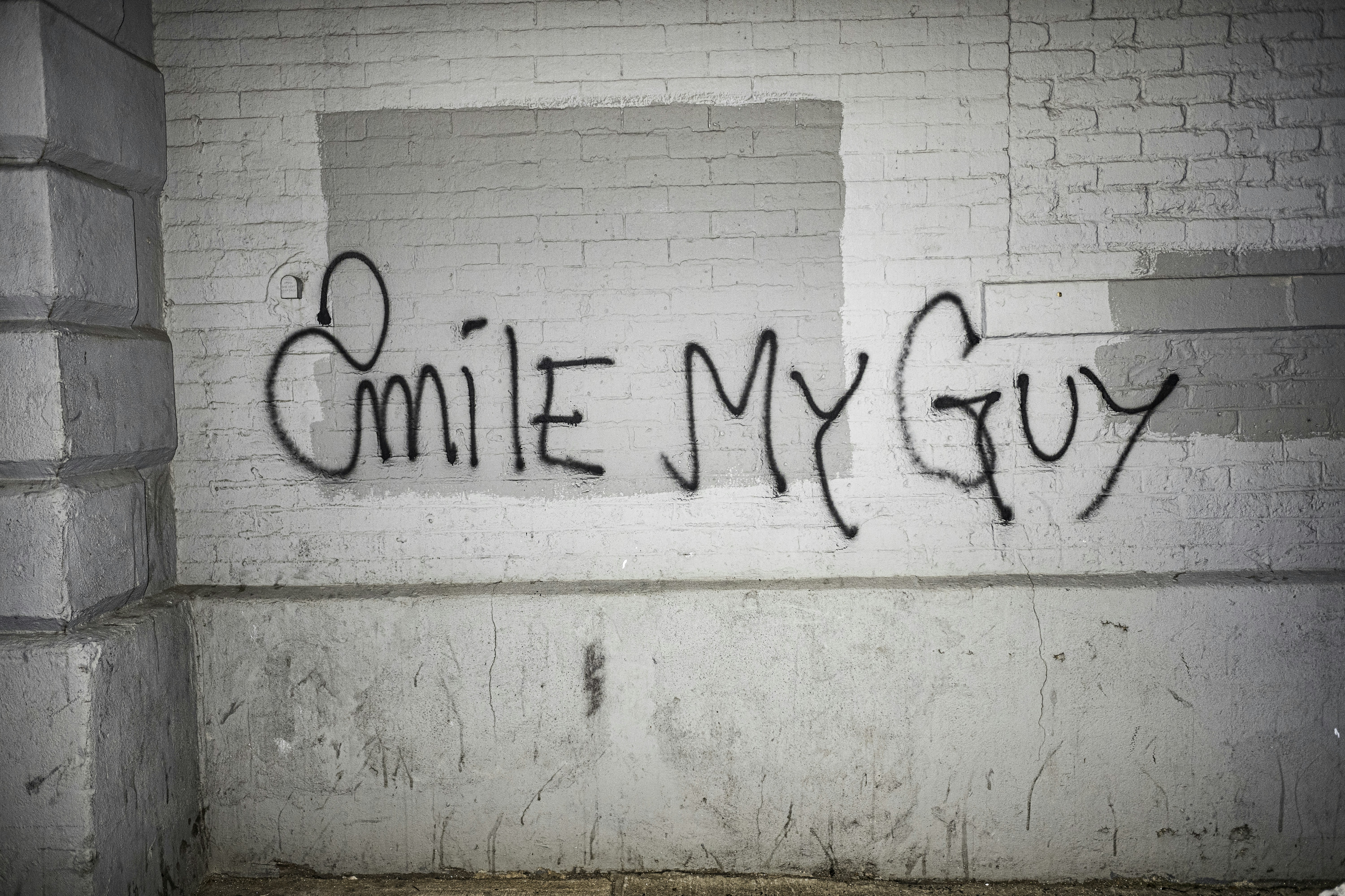 Graffiti on a brick wall says "smile my guy". (Photo by New York Said on Unsplash)