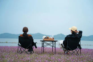 Two people sitting in chairs facing a lake