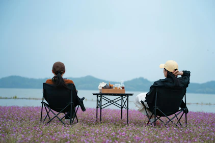 Two people sitting in chairs facing a lake