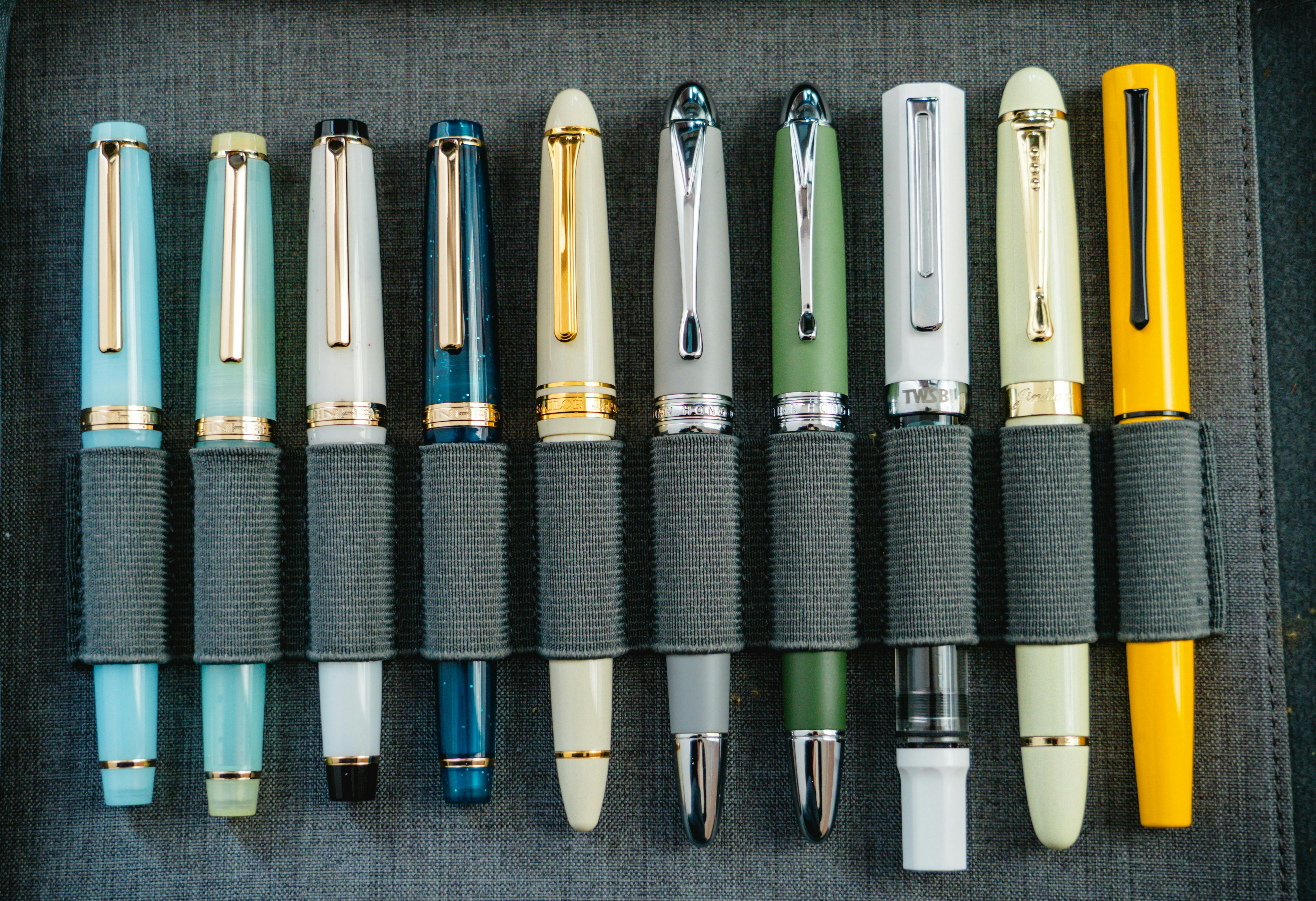 A collection of colorful fountain pens in a holder.