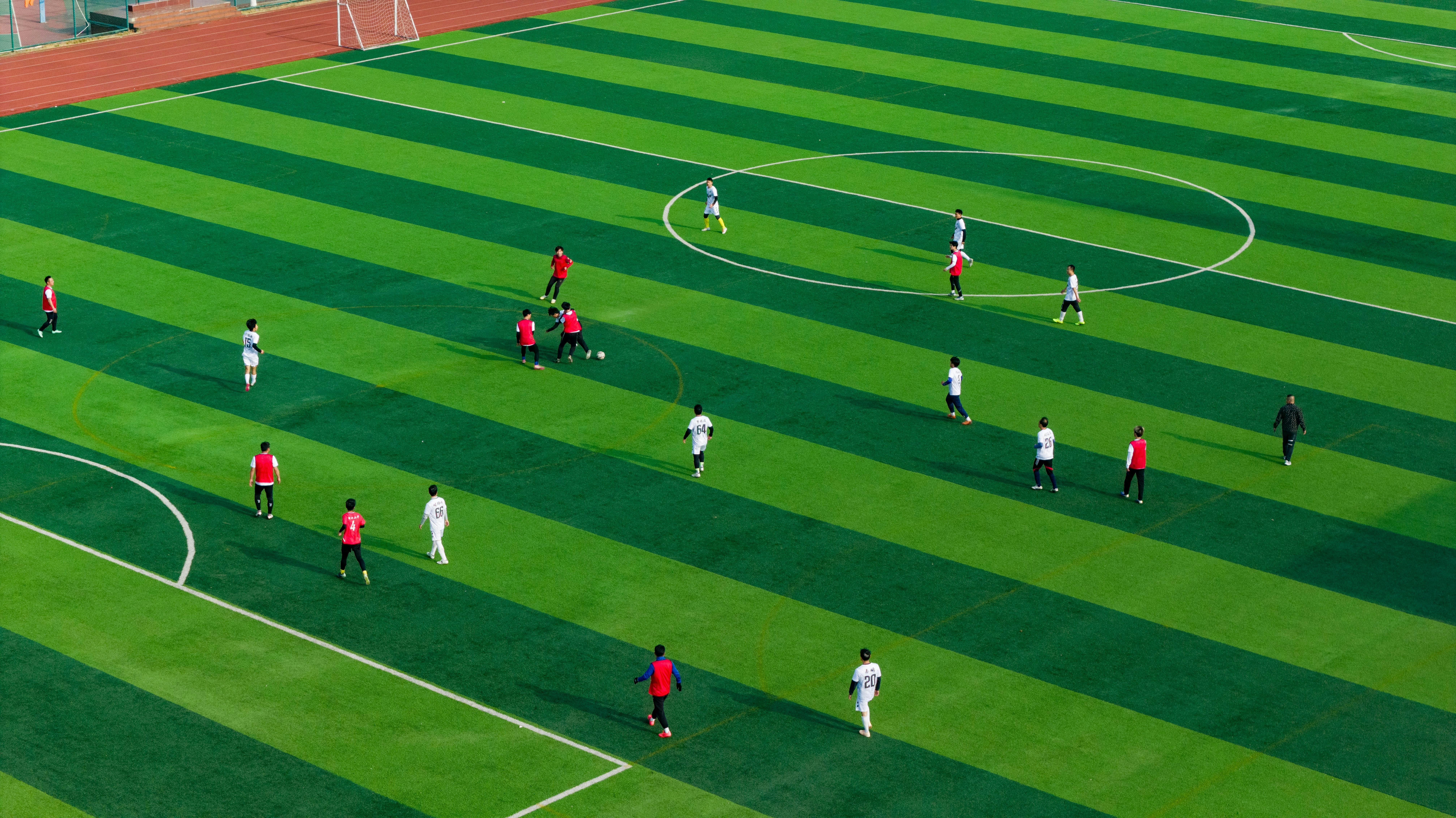 Pemain di lapangan sepak bola hijau bergaris selama pertandingan.