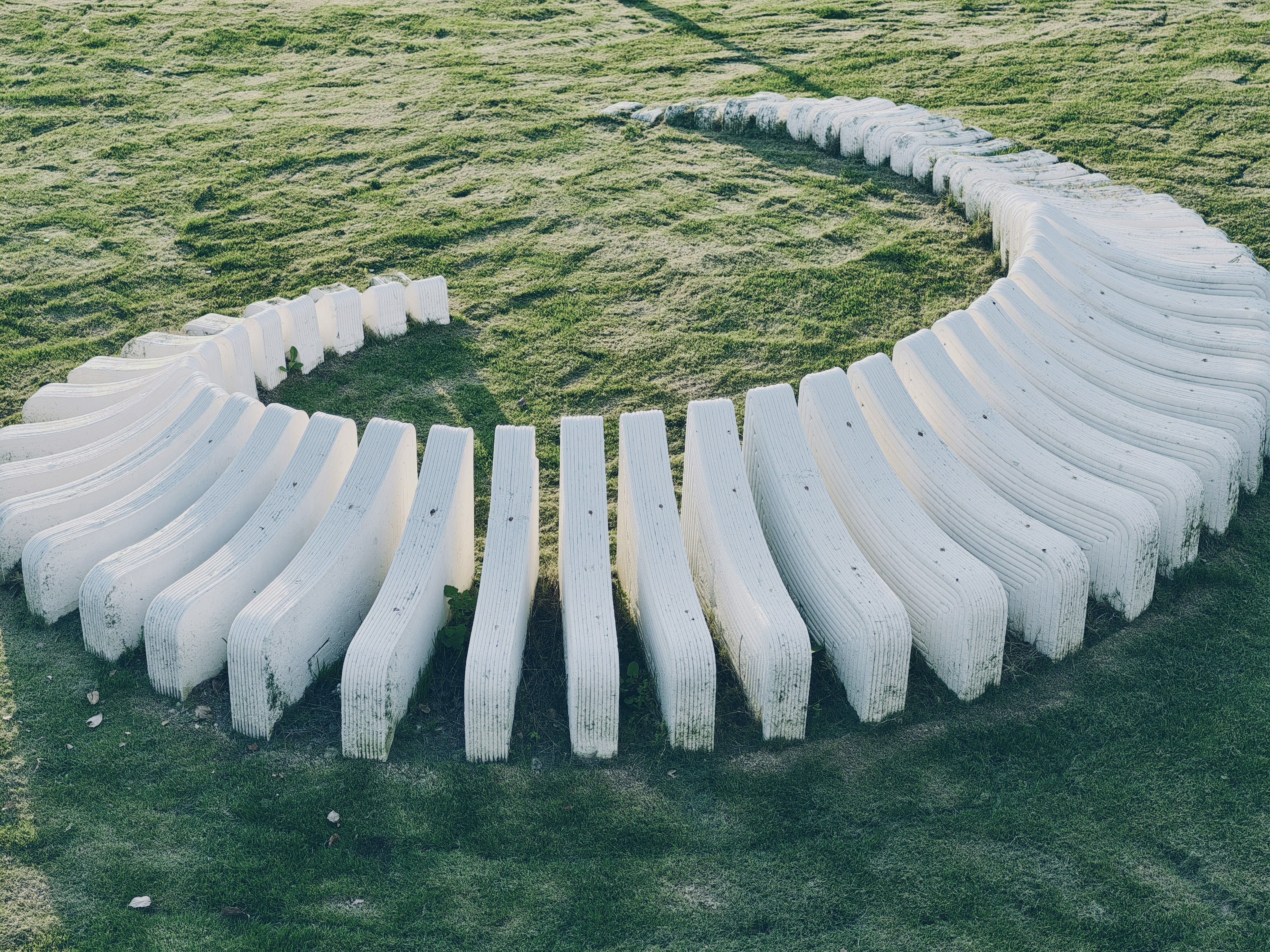 Curved white stone sculpture on grassy field