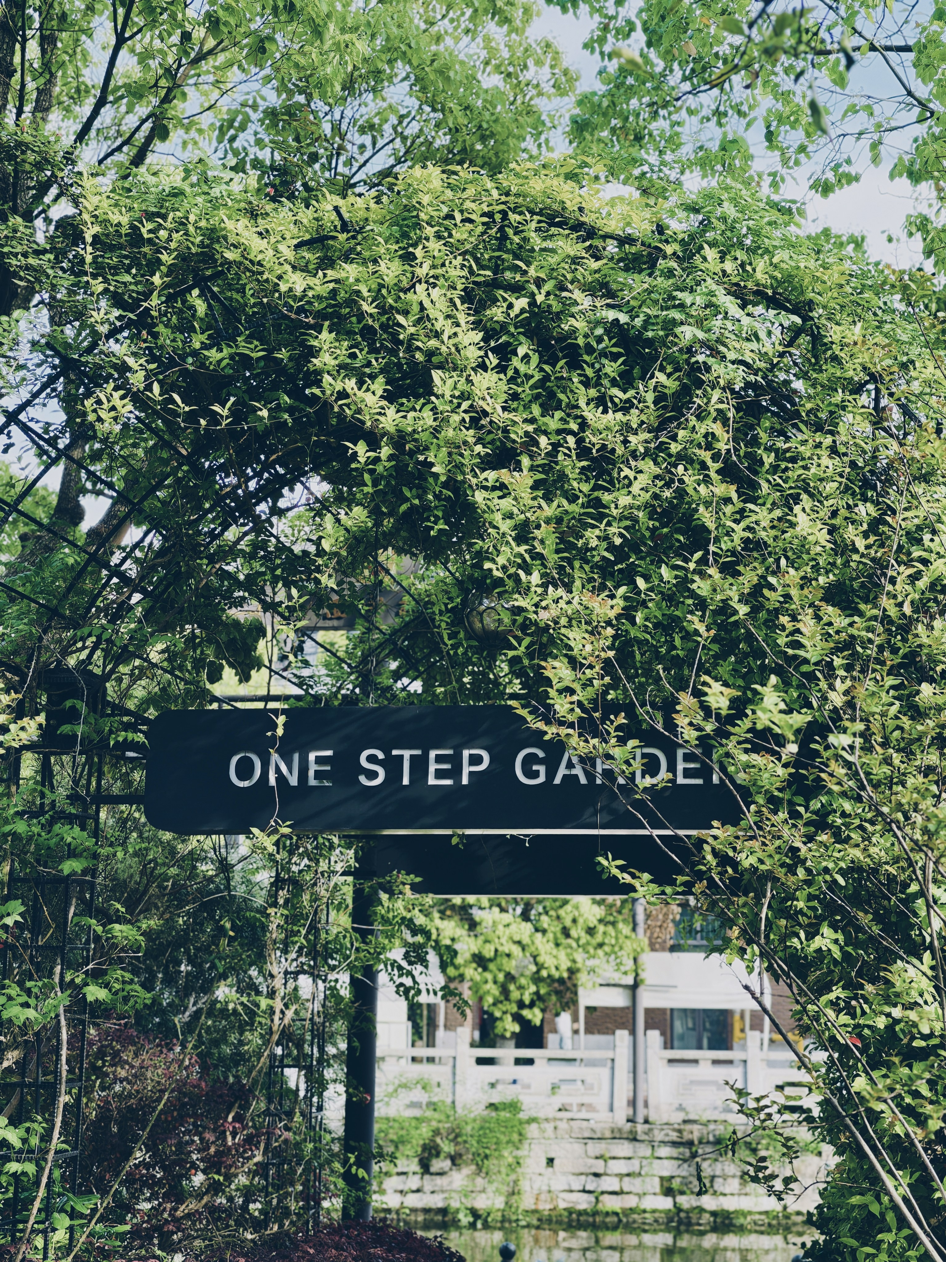 A sign for "one step garden" amidst lush greenery