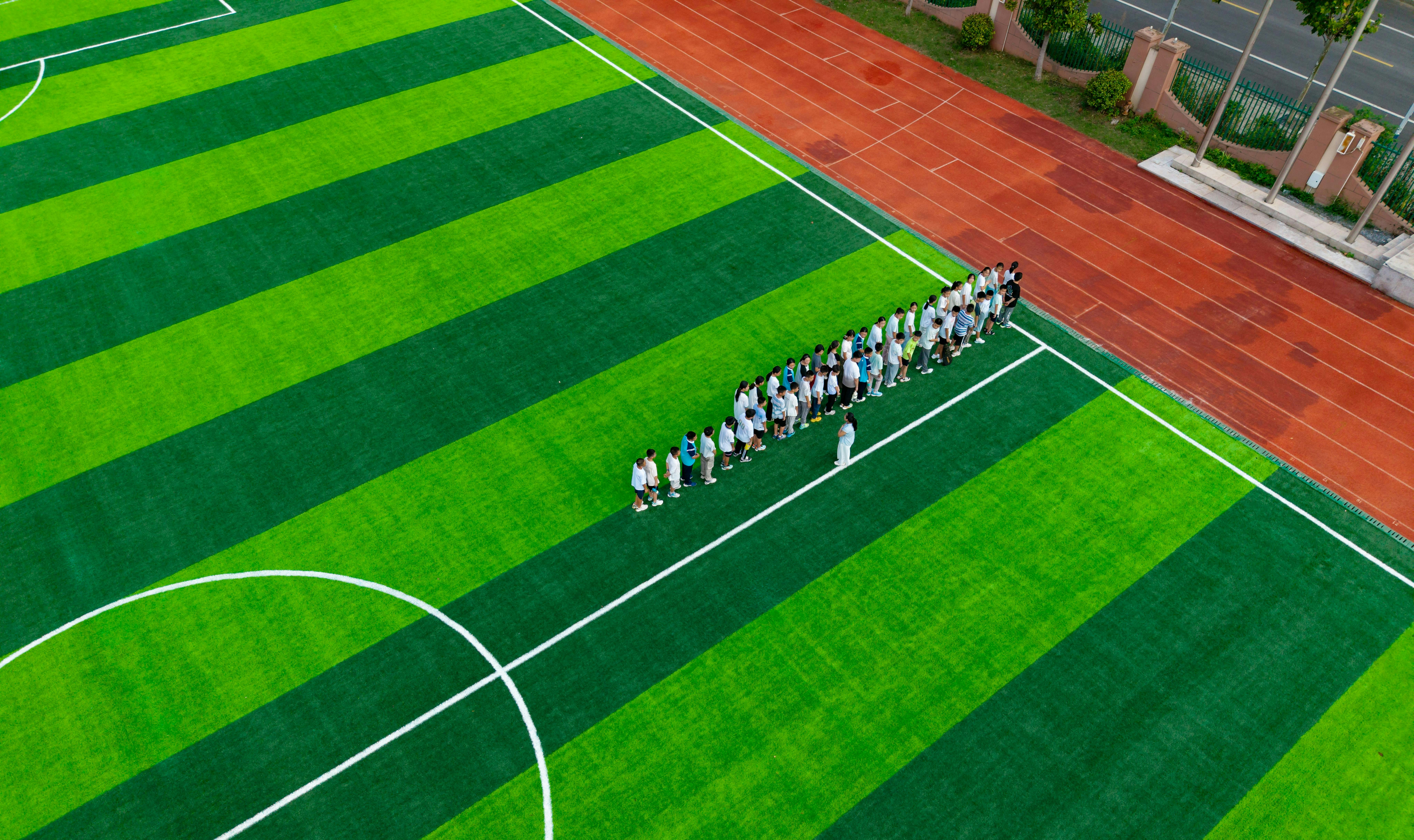 A group of people standing on a green soccer field.