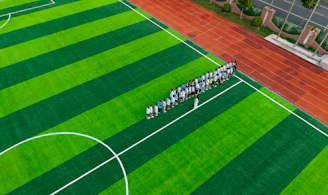 A group of people standing on a green soccer field.