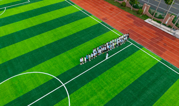 A group of people standing on a green soccer field.