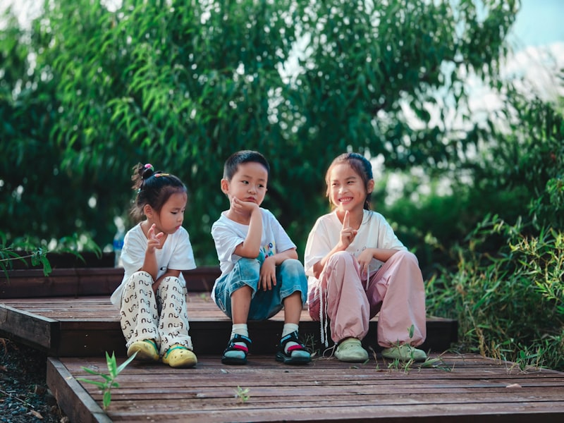 Three children sitting on wooden steps outdoors